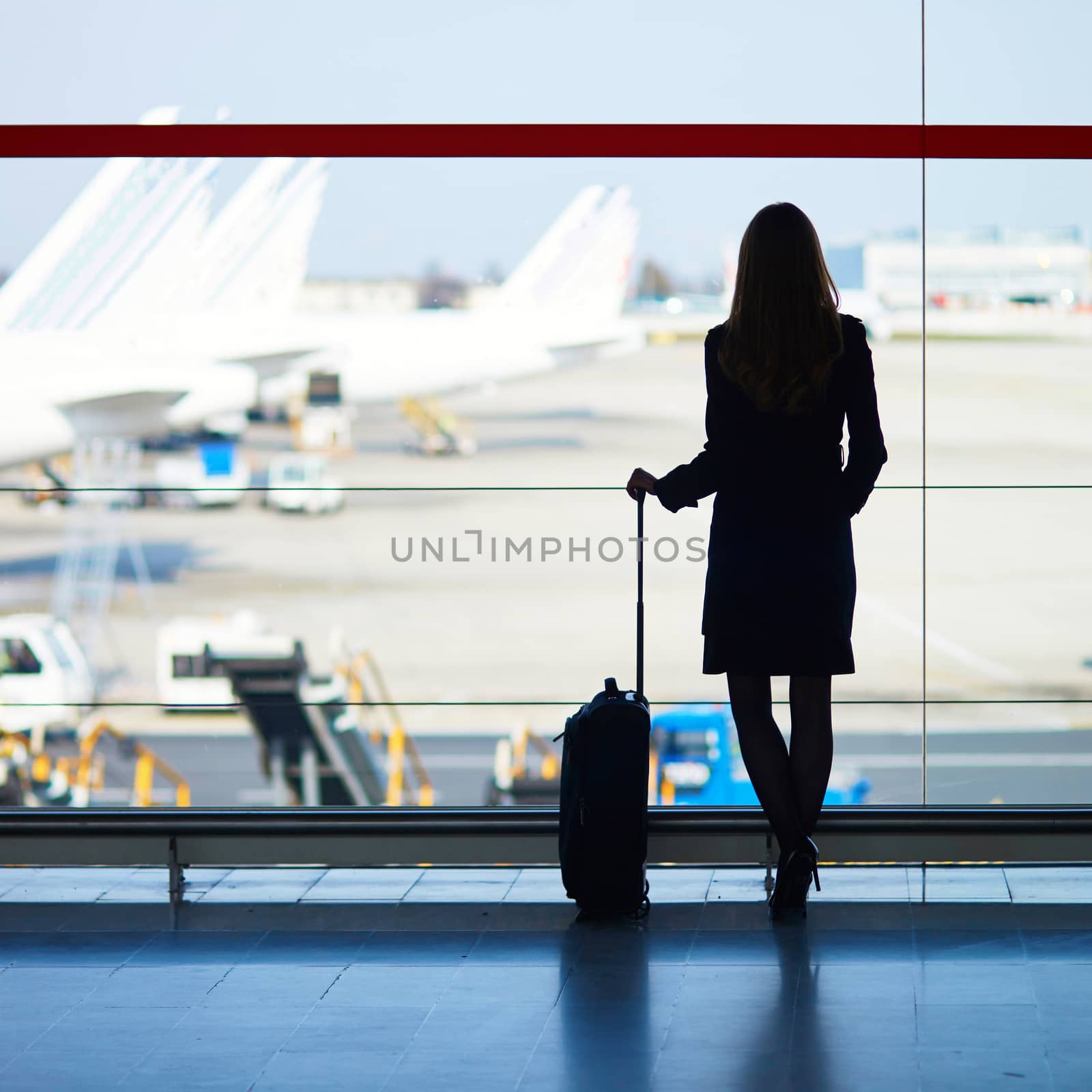Young woman in international airport looking at planes through the window