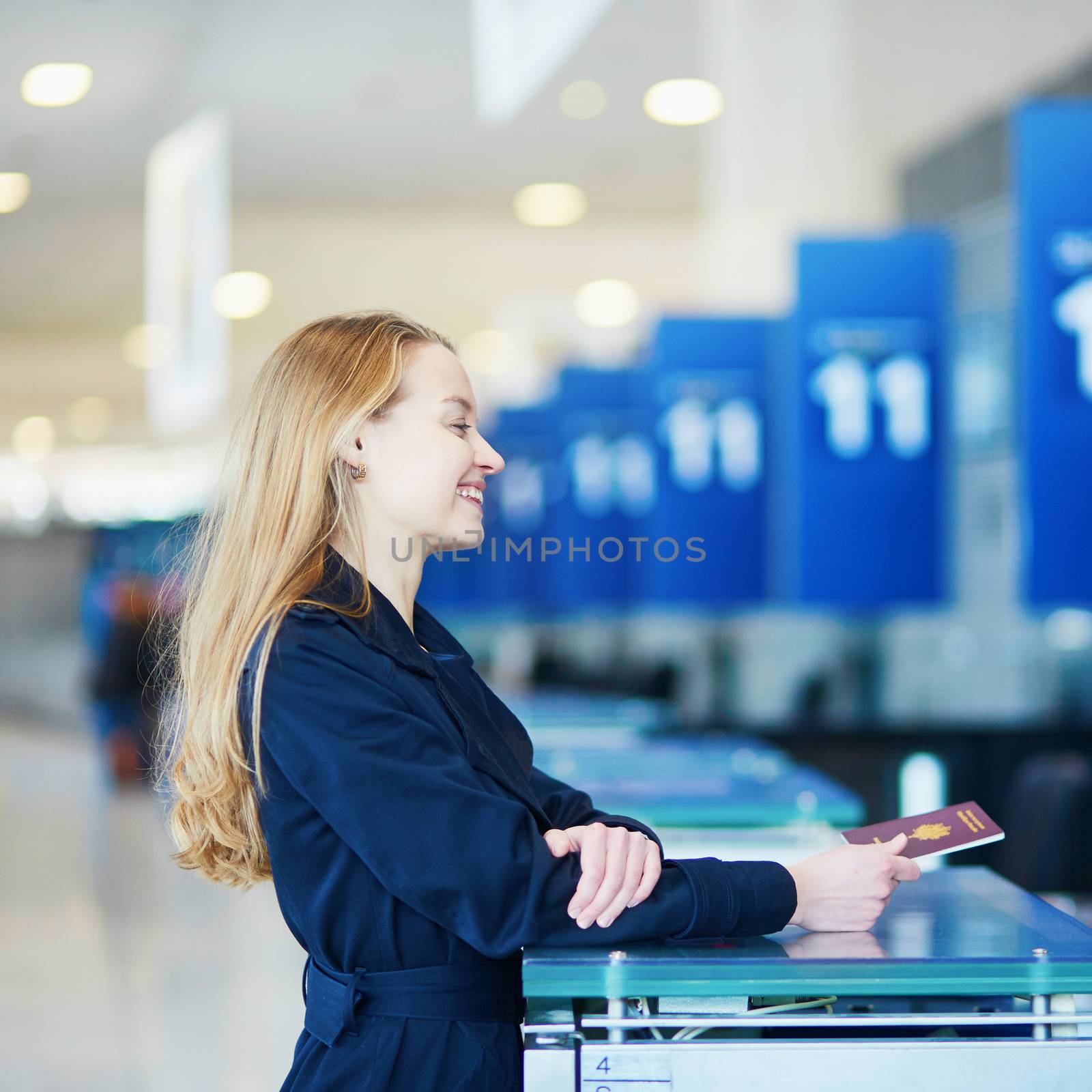 Woman in international airport at check-in counter, giving her passport by jaspe