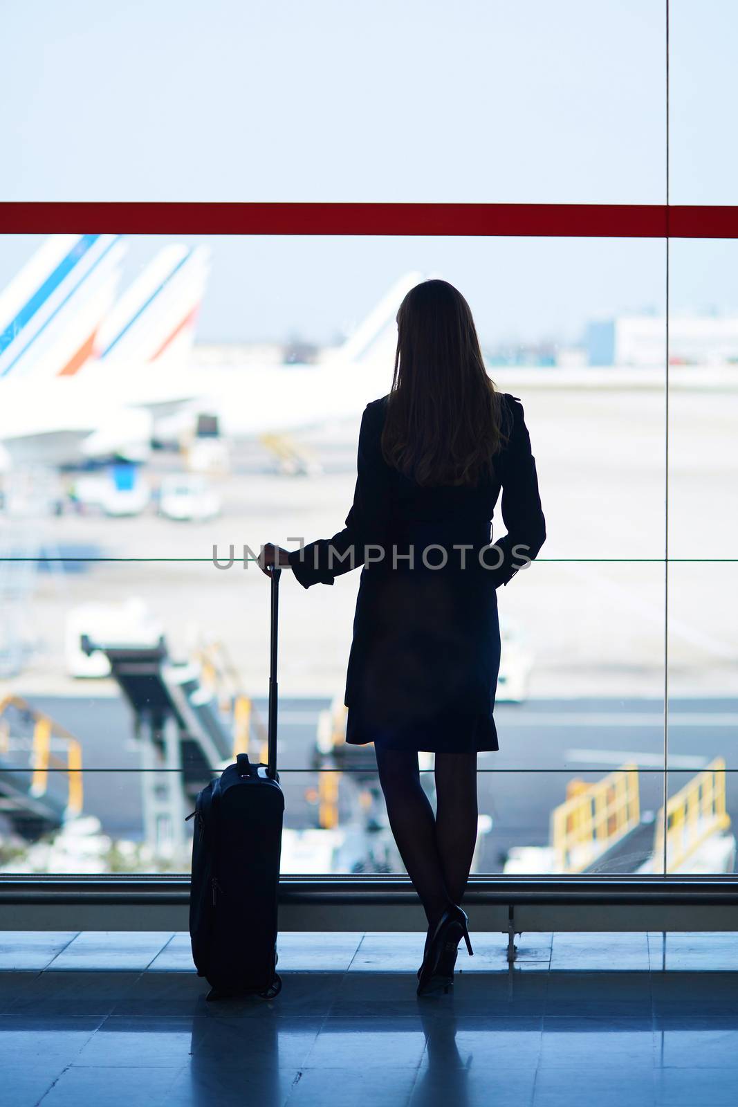 Young woman in the airport, looking through the window at planes