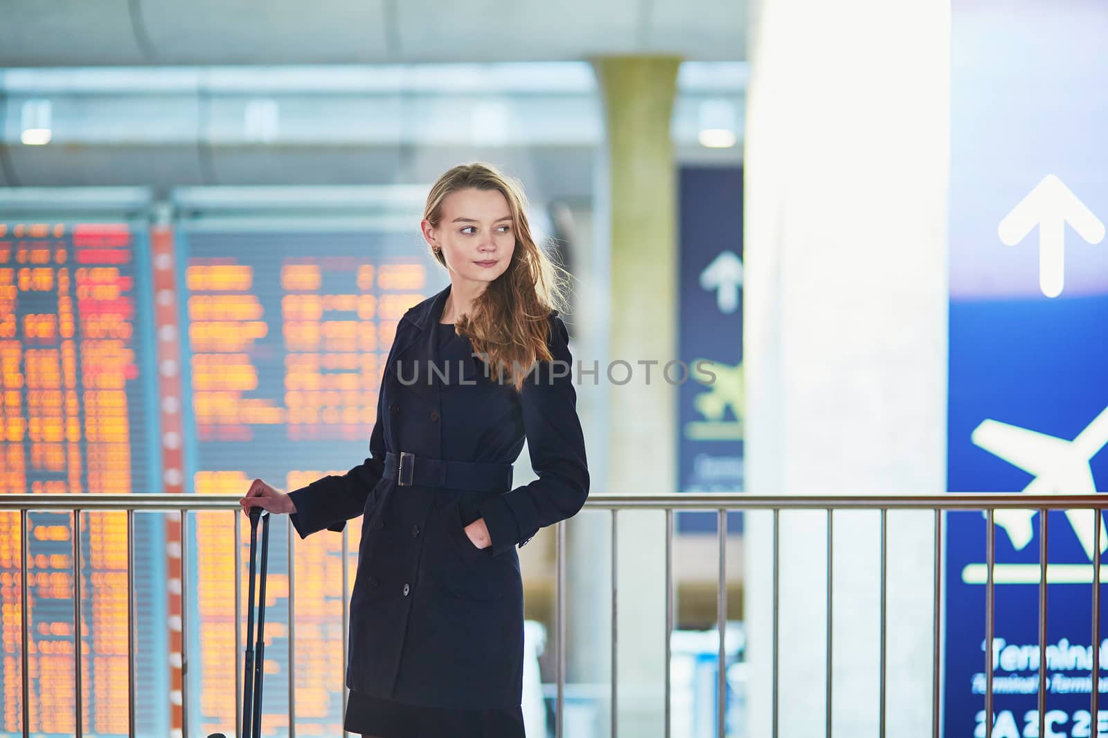 Young woman in international airport near the flight information board, checking her passport