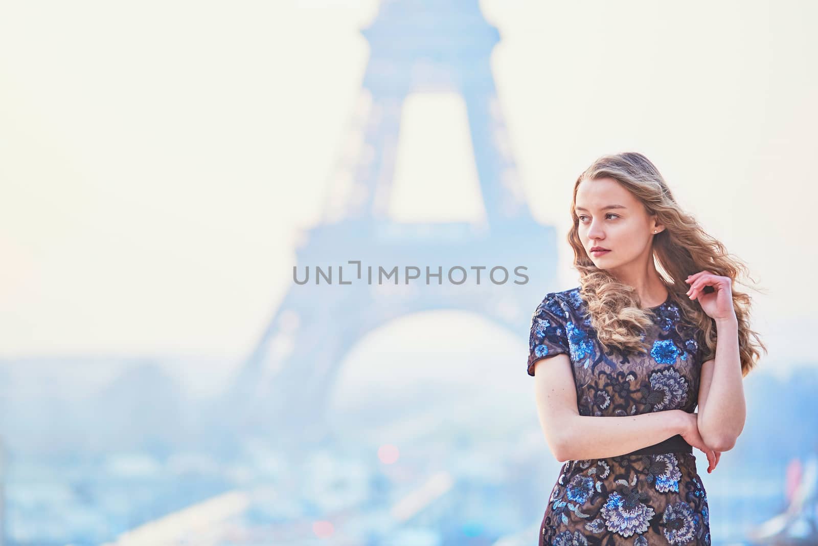 Beautiful elegant Parisian woman near the Eiffel tower at early morning