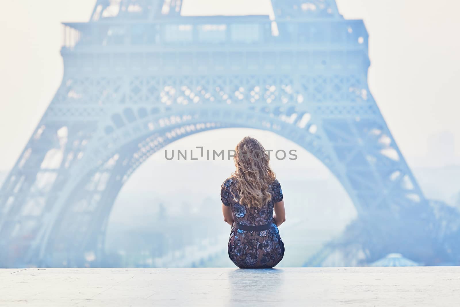 Beautiful elegant Parisian woman near the Eiffel tower at early morning
