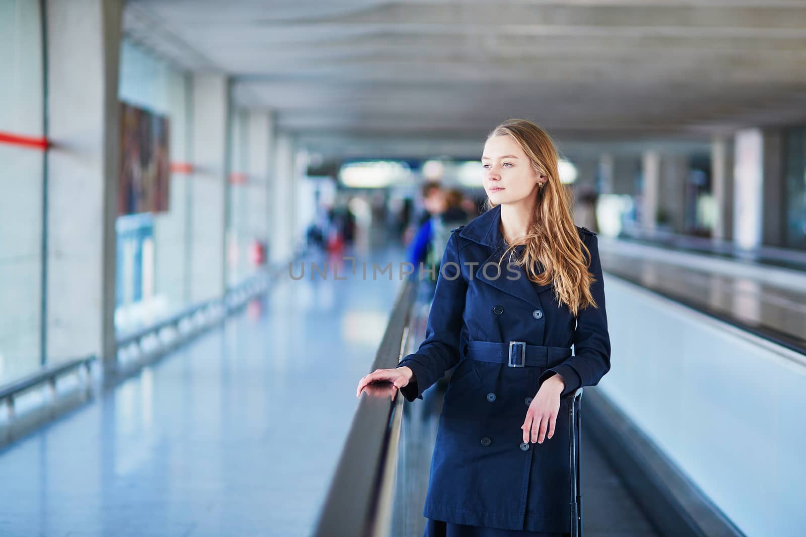 Young woman in international airport walking along the travelator