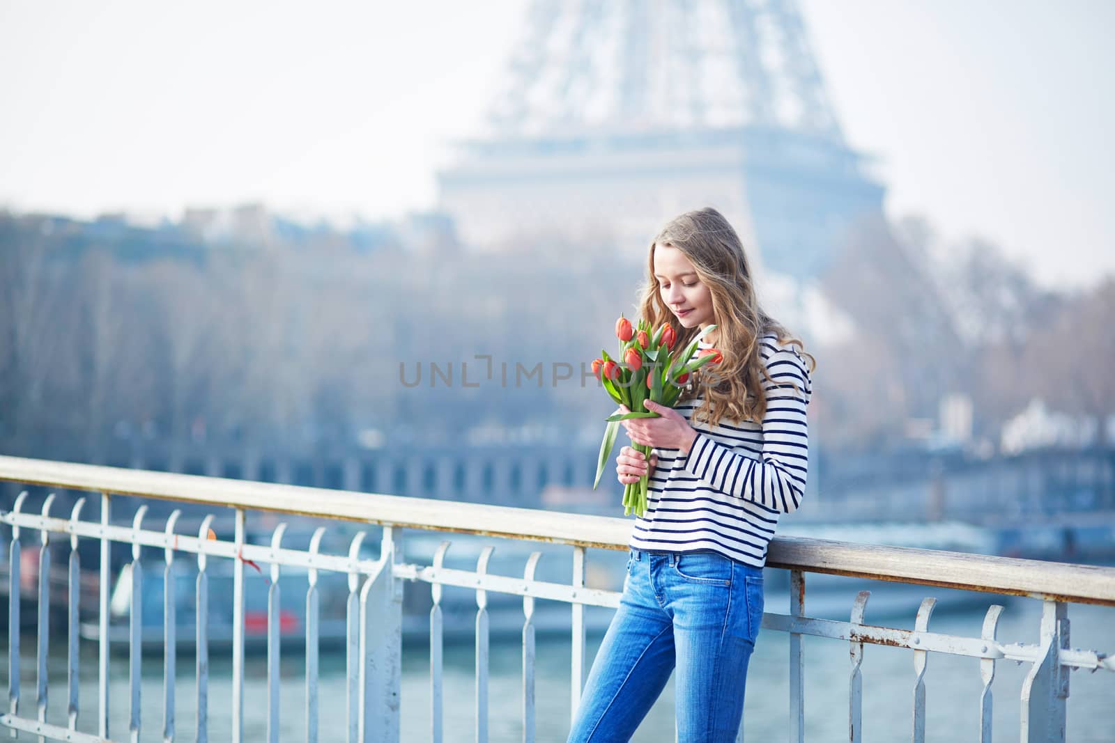 Beautiful young girl with bunch of red tulips near the Eiffel tower