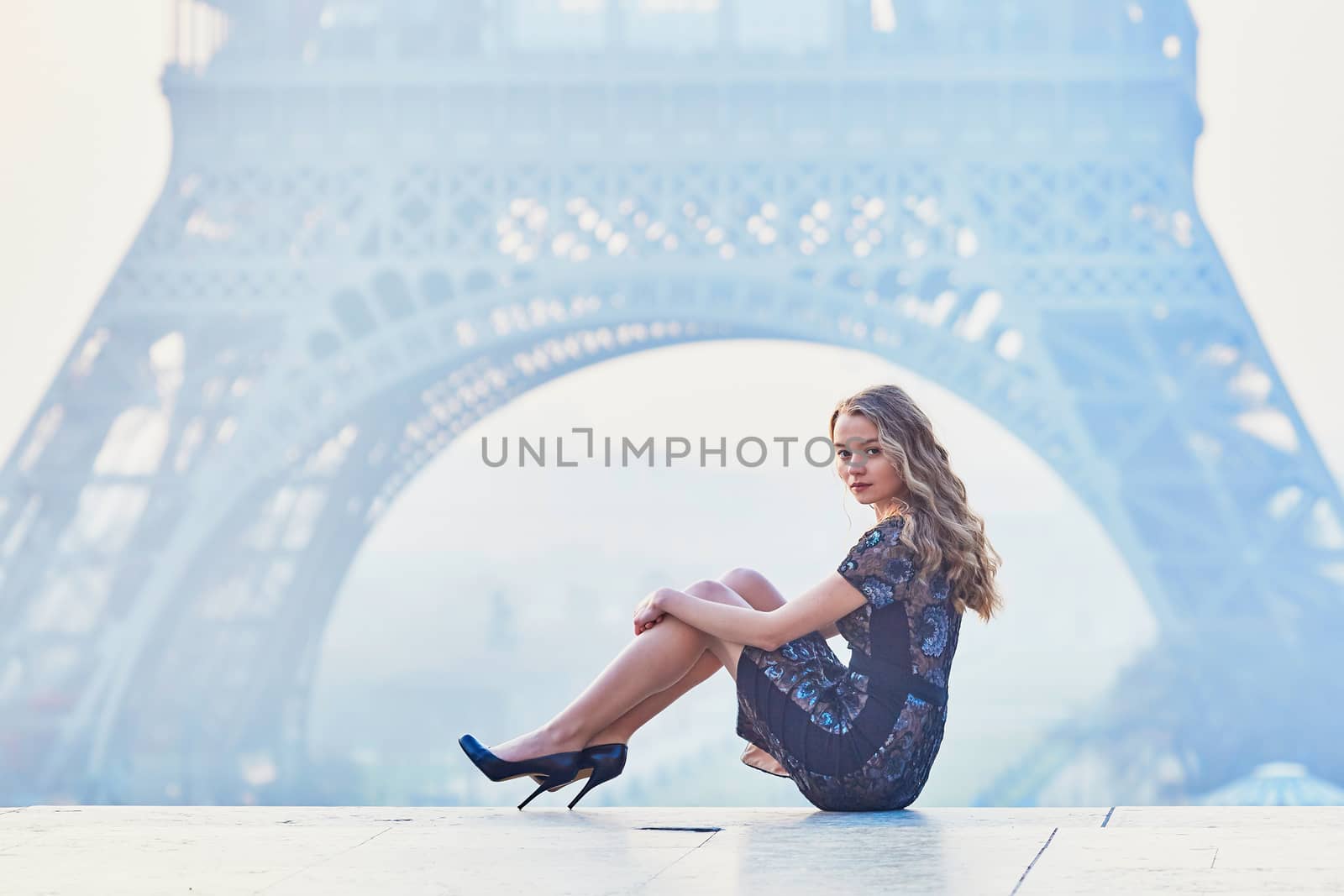 Beautiful elegant Parisian woman near the Eiffel tower at early morning