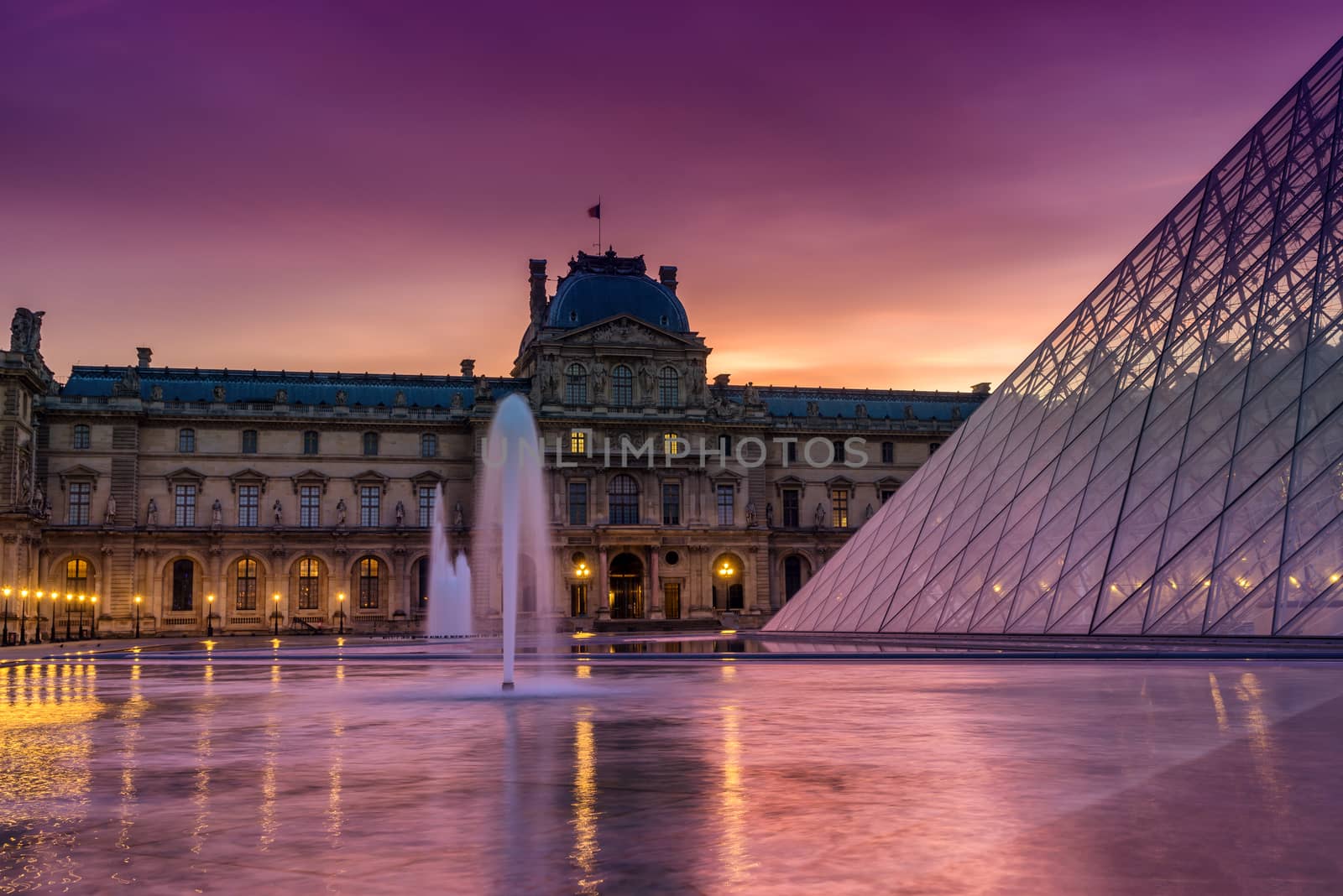 PARIS, FRANCE - DECEMBER 9, 2016: View of famous Louvre Museum with Louvre Pyramid at evening. Louvre Museum is one of the largest and most visited museums worldwide.