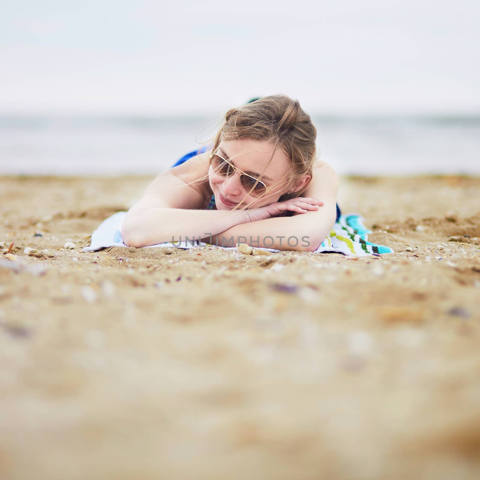 Beautiful young woman relaxing and sunbathing on sand beach