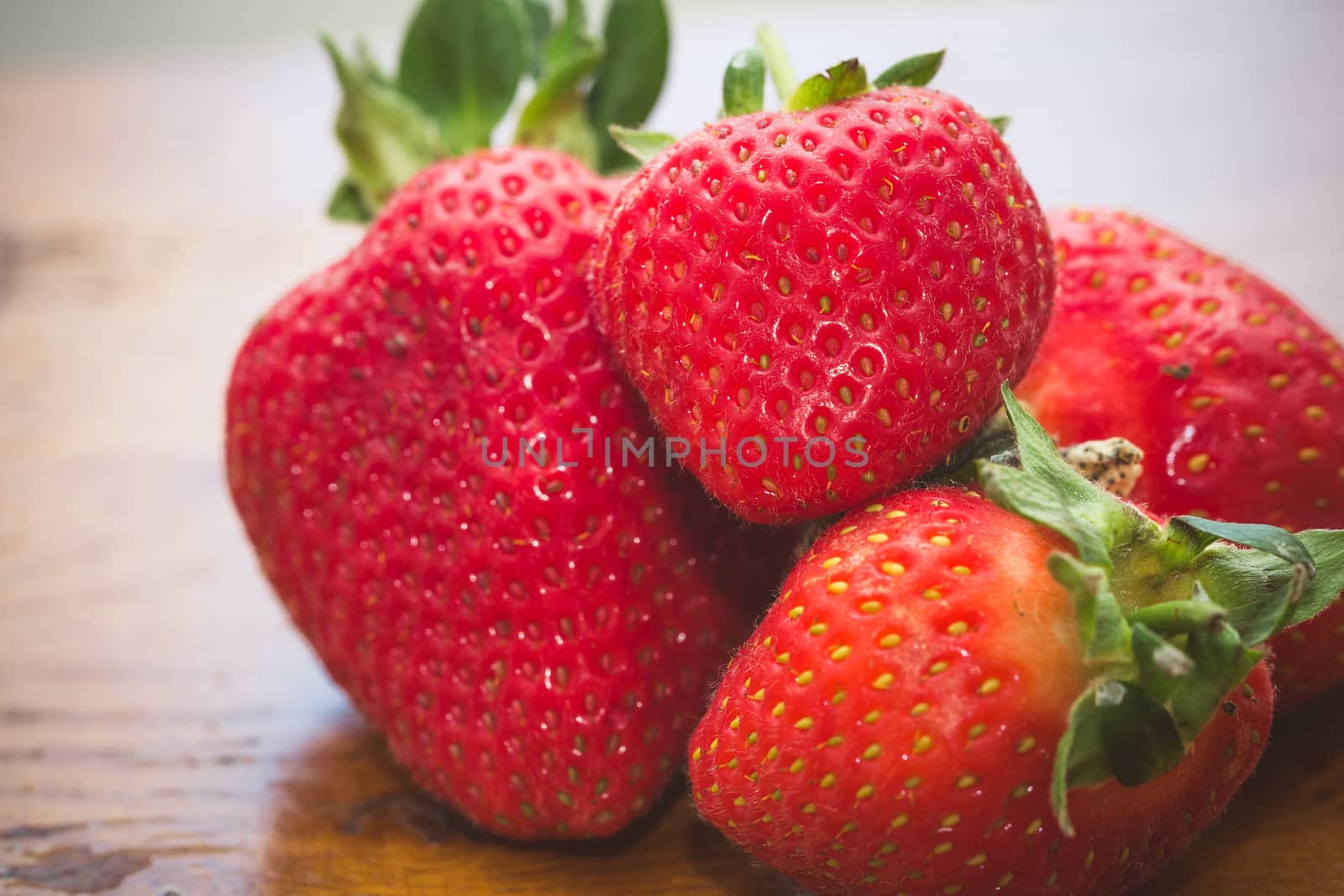 A pile of strawberries on a wooden table