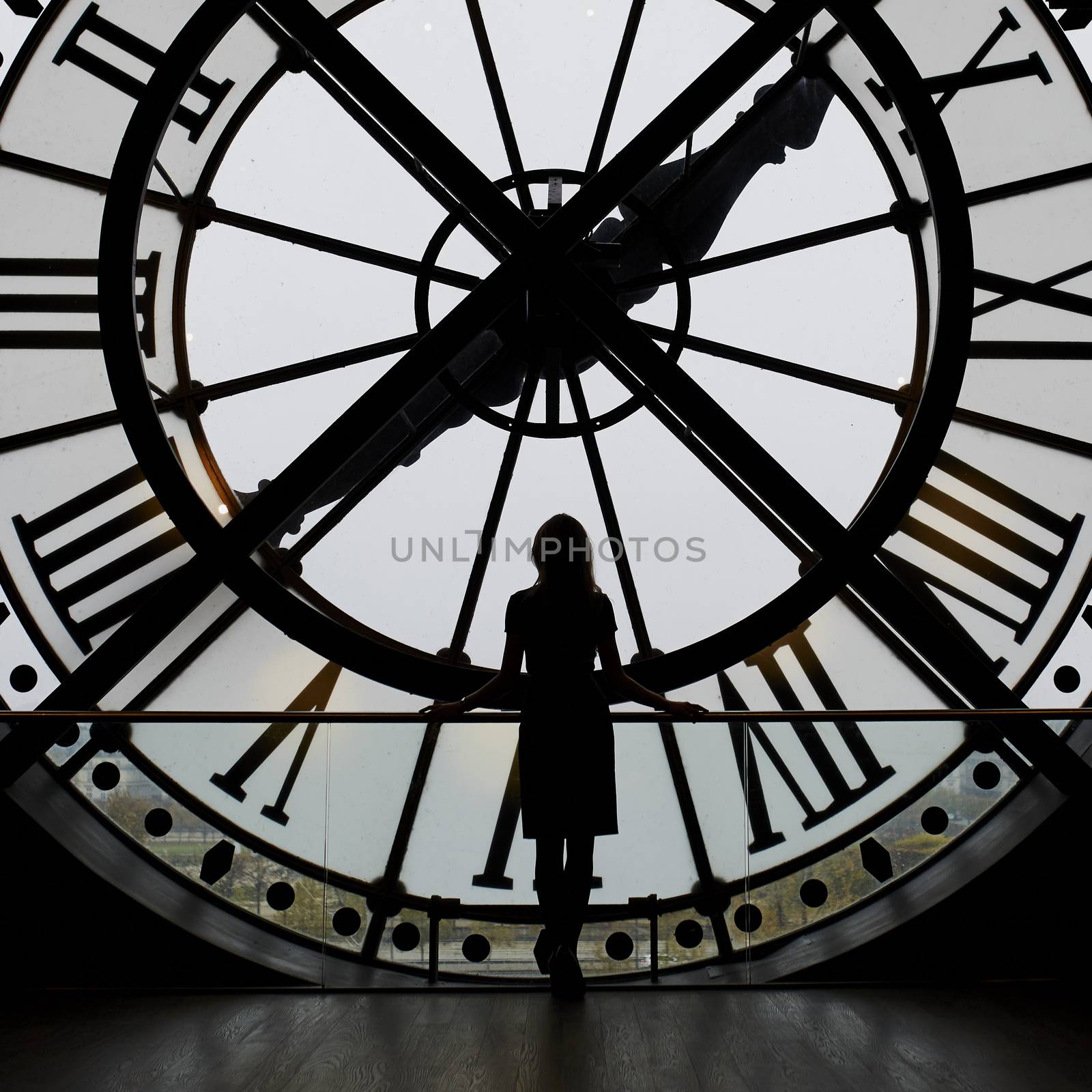 Woman silhouette standing in front of clock in the Orsay Museum, Paris, France. Unrecognizable person overlooking Paris