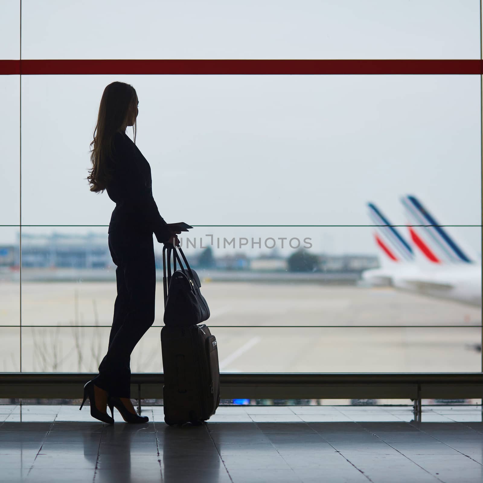 Young woman in international airport looking at planes through the window