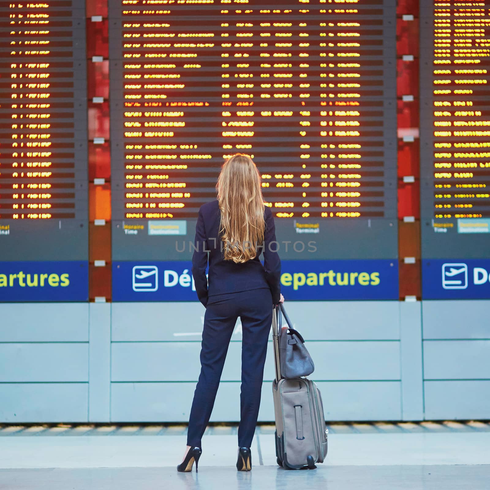 Young woman in international airport near large information display