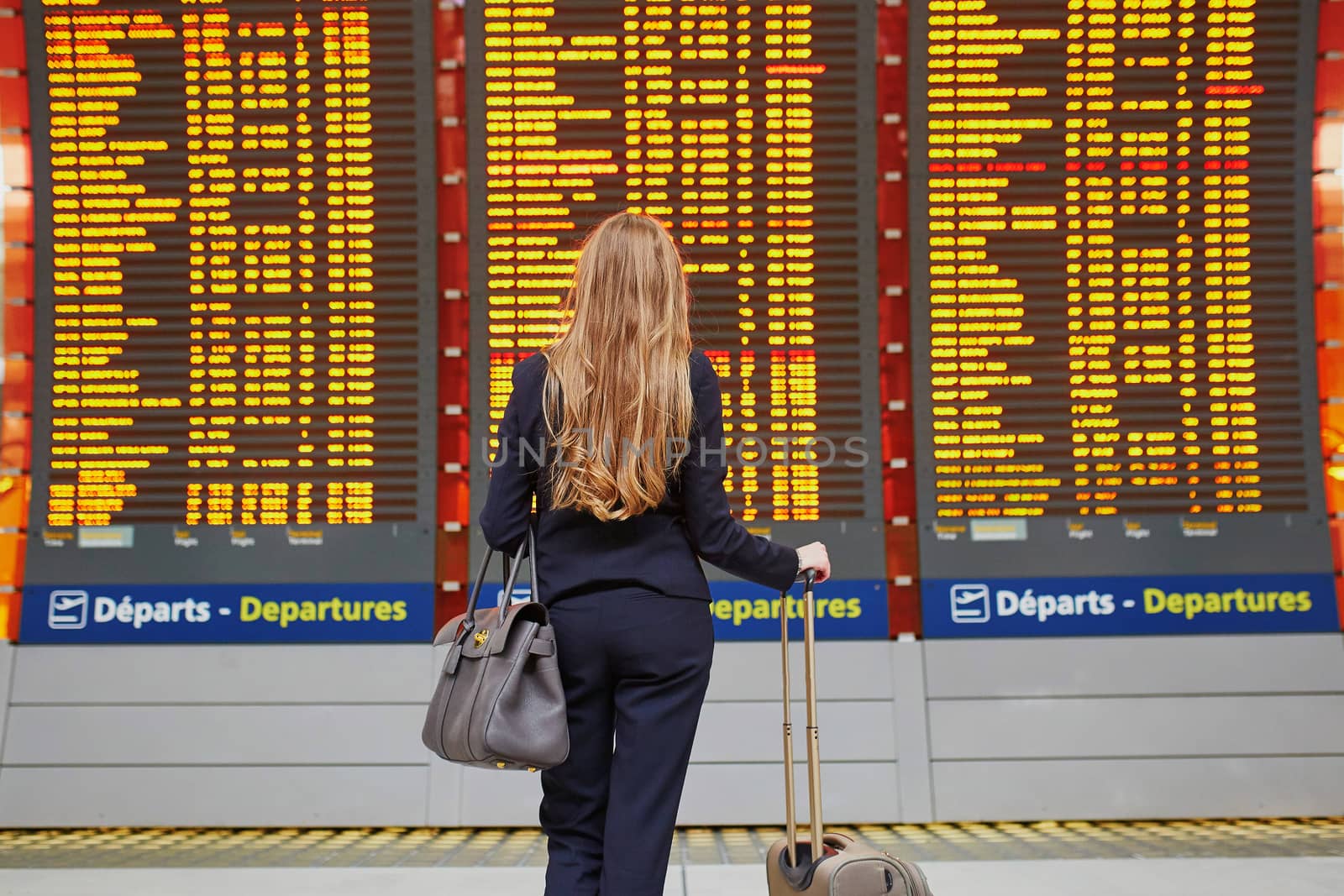 Young woman in international airport near large information display