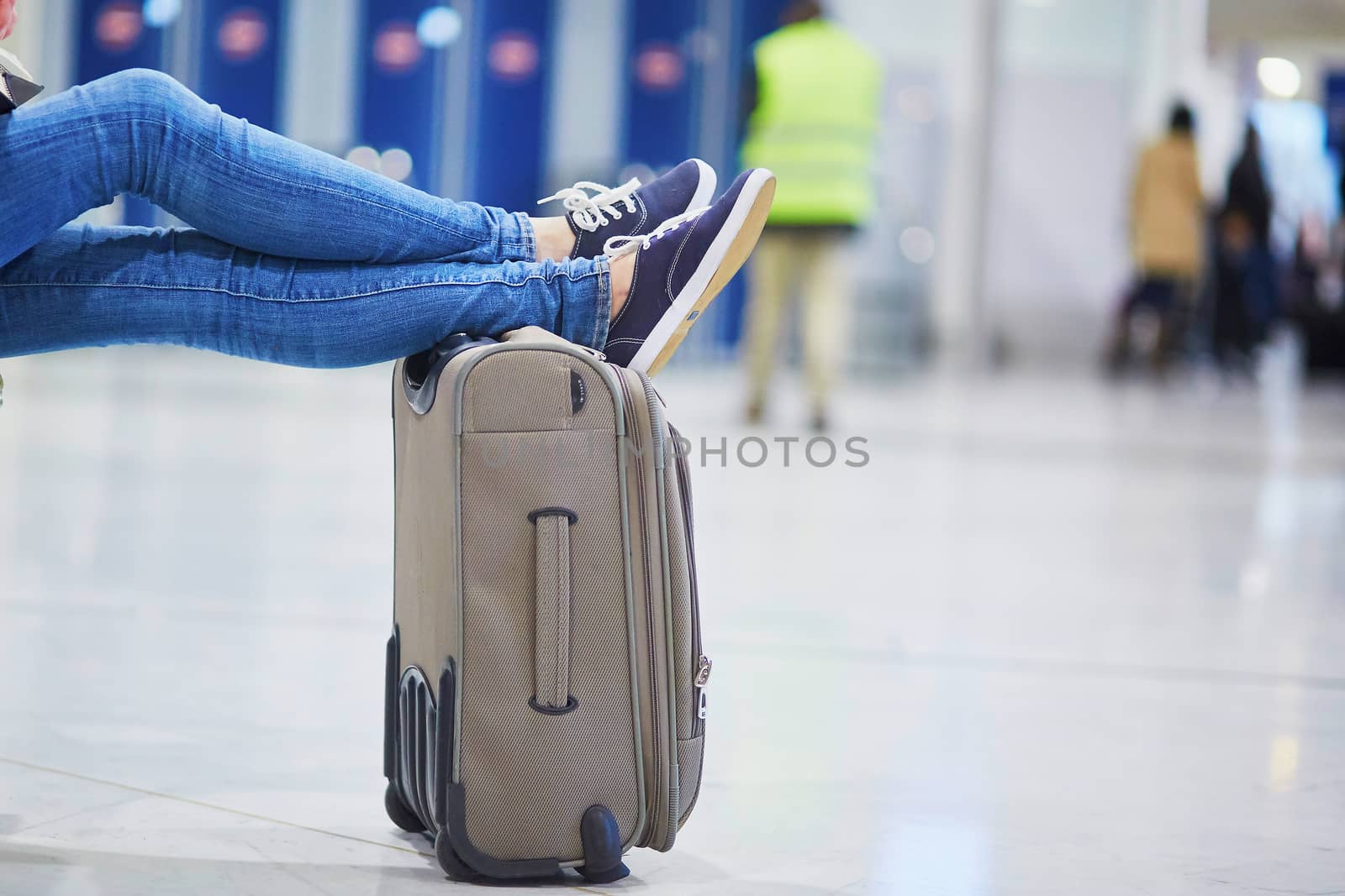 Closeup of woman feet on a suitcase in international airport. Delayed or canceled flight concept