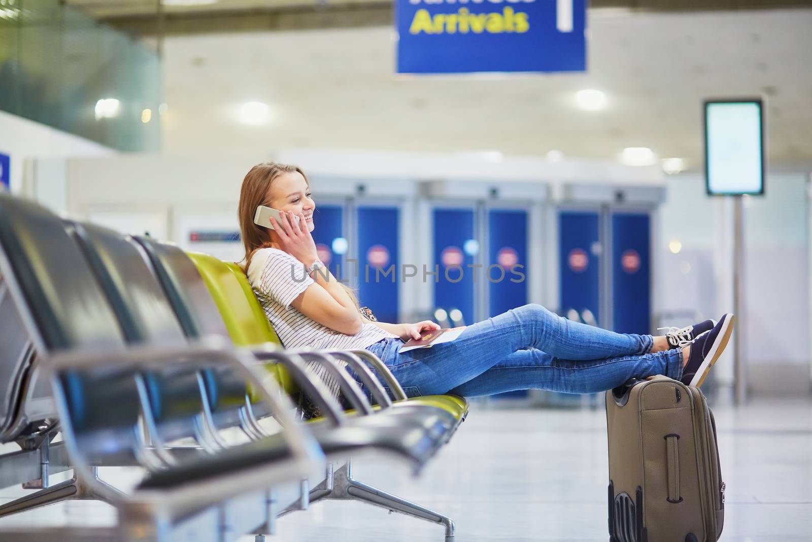 Young woman in international airport using mobile phone while waiting for her flight