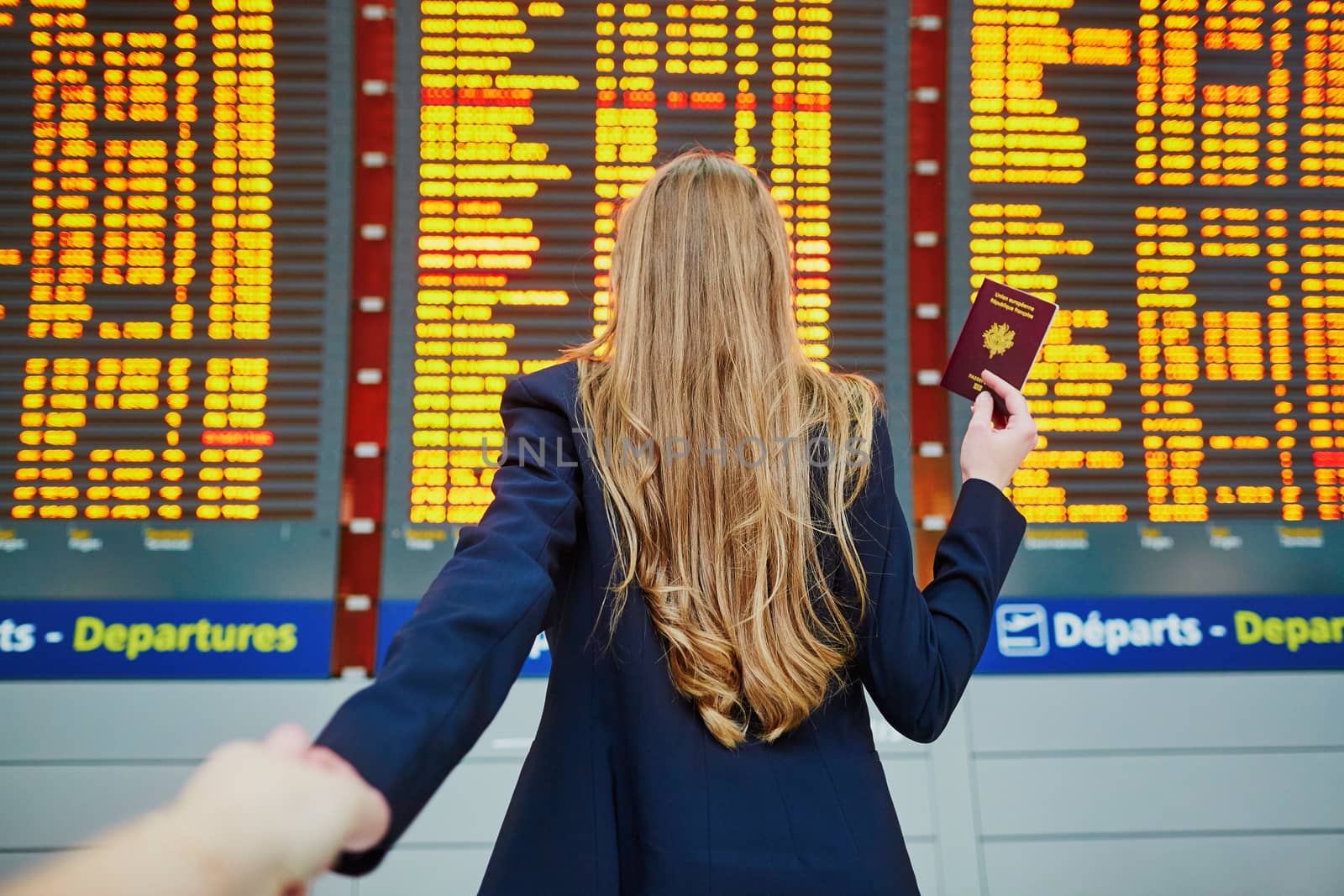 Young woman in international airport near large information display, follow me concept