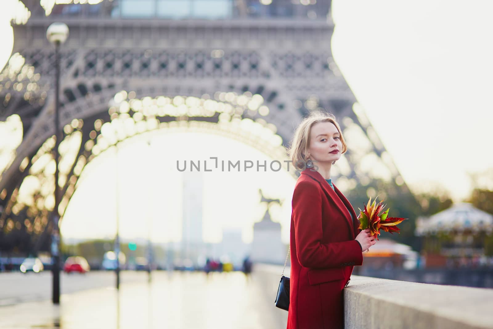 Beautiful young French woman drinking coffee near the Eiffel tower in Paris on a fall or spring day