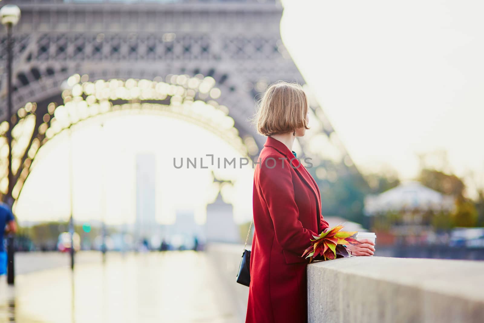Beautiful young French woman drinking coffee near the Eiffel tower in Paris on a fall or spring day