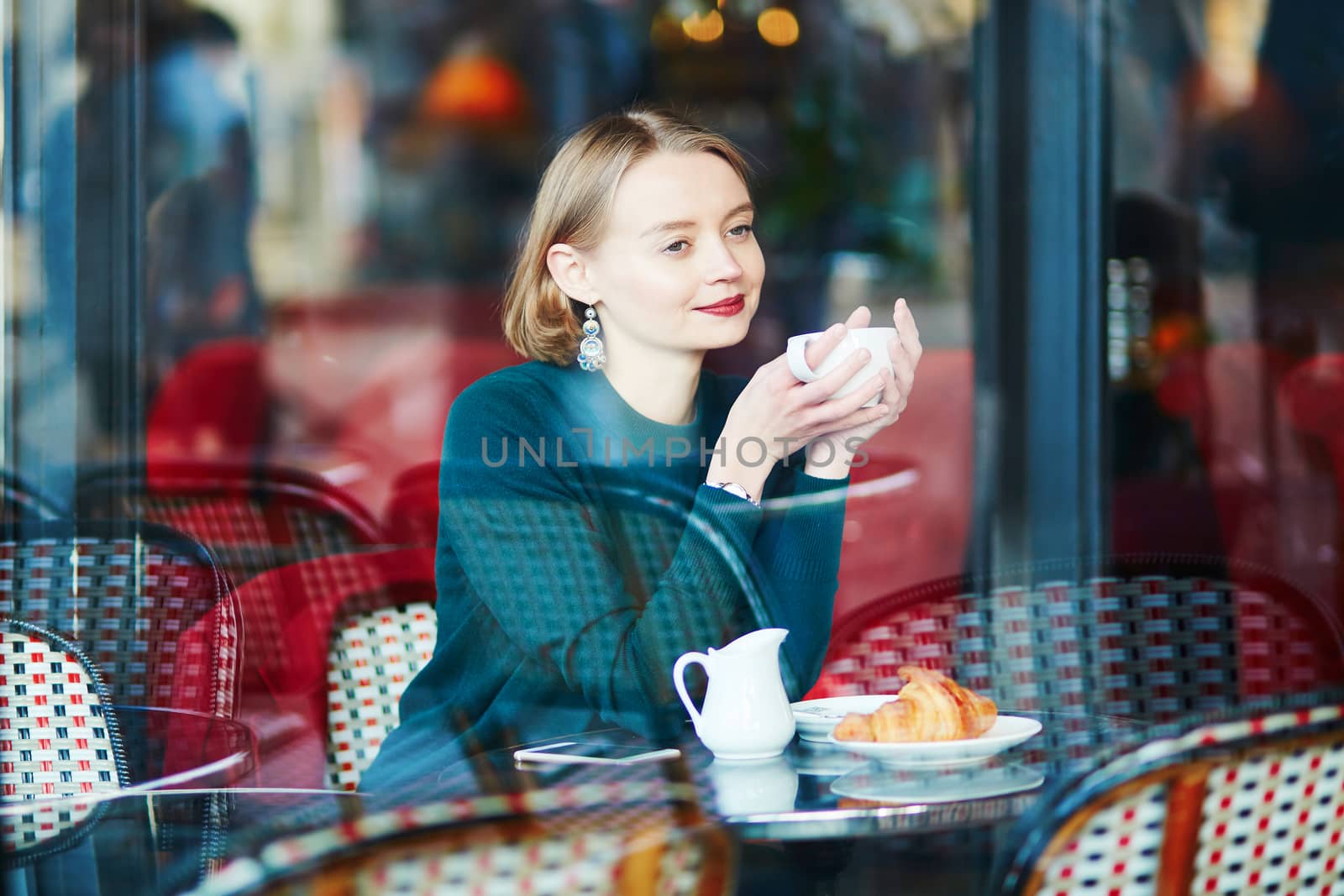 Young elegant woman drinking coffee in traditional cafe in Paris, France