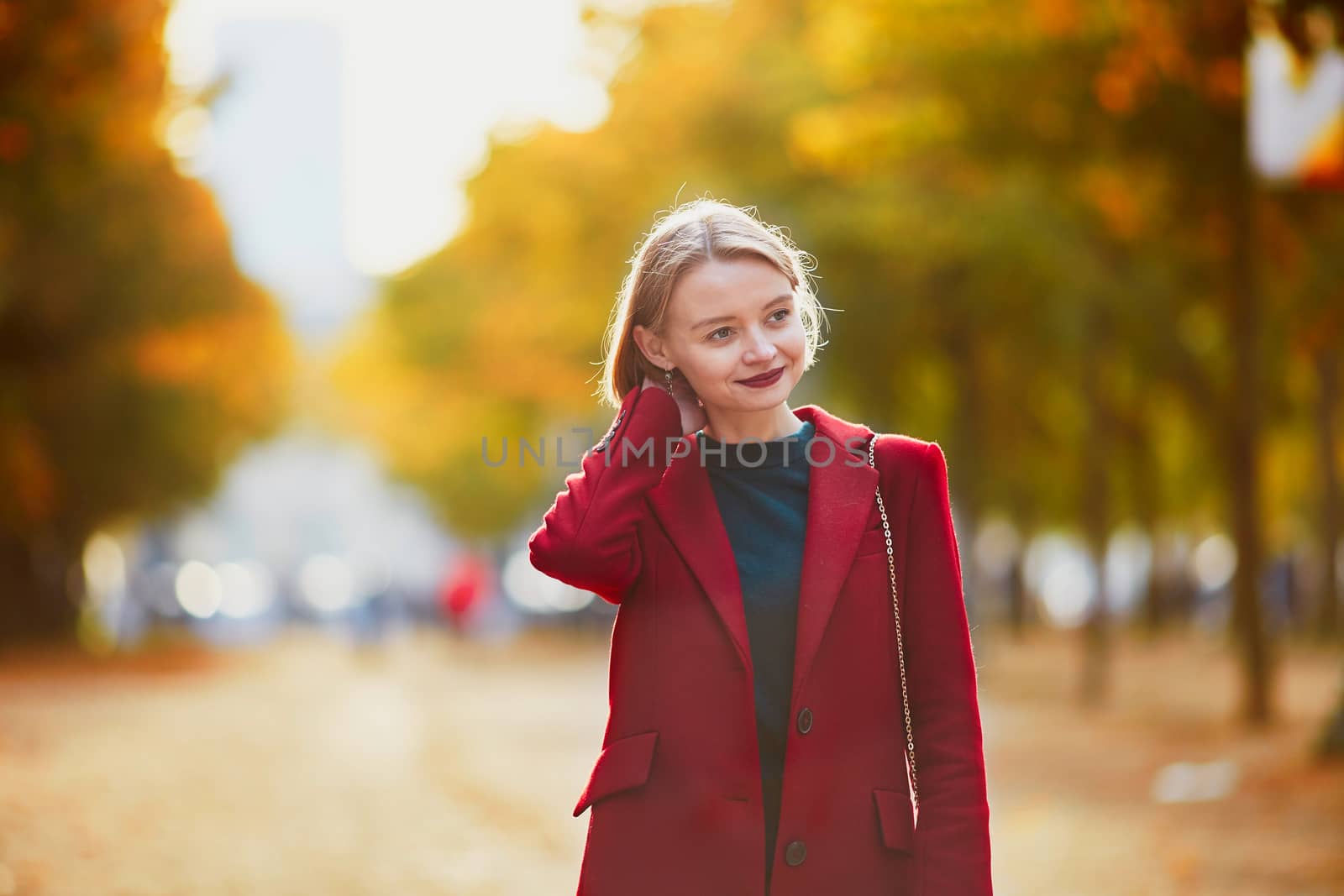 Beautiful young woman with bunch of colorful autumn leaves walking in park on a fall day