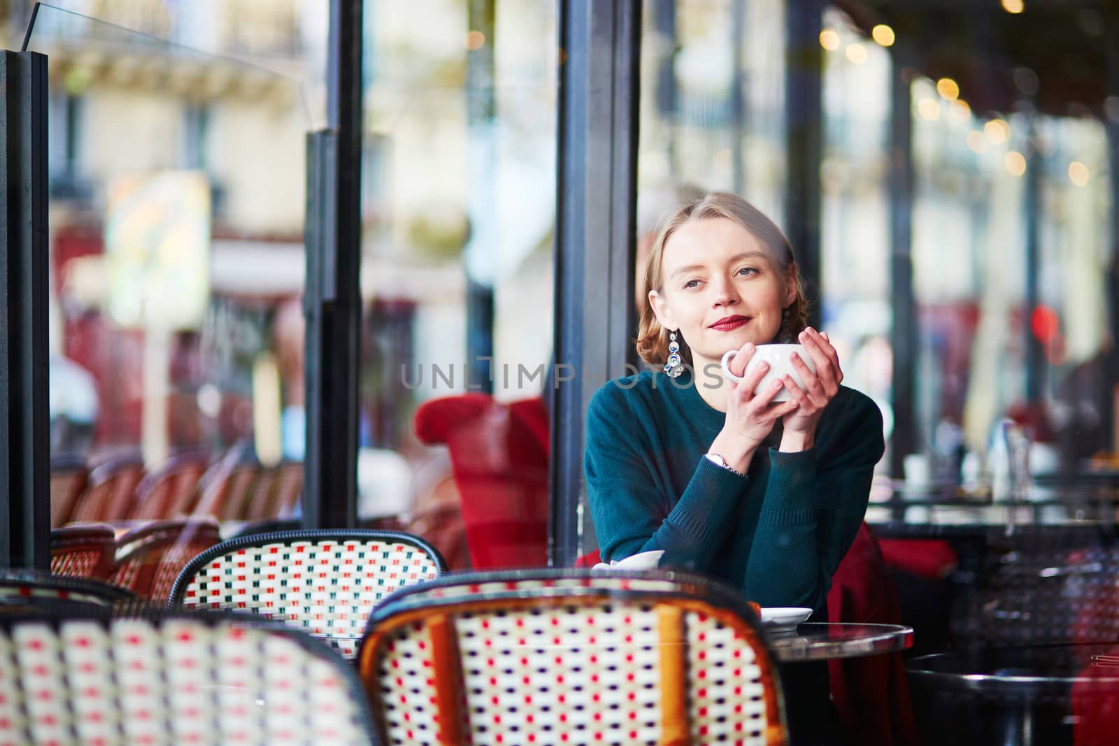Young elegant woman drinking coffee in traditional cafe in Paris, France