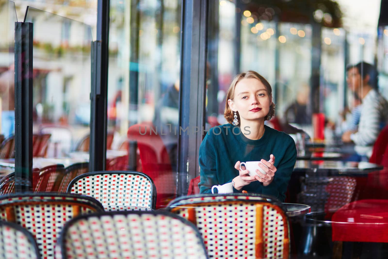 Young elegant woman drinking coffee in traditional cafe in Paris, France