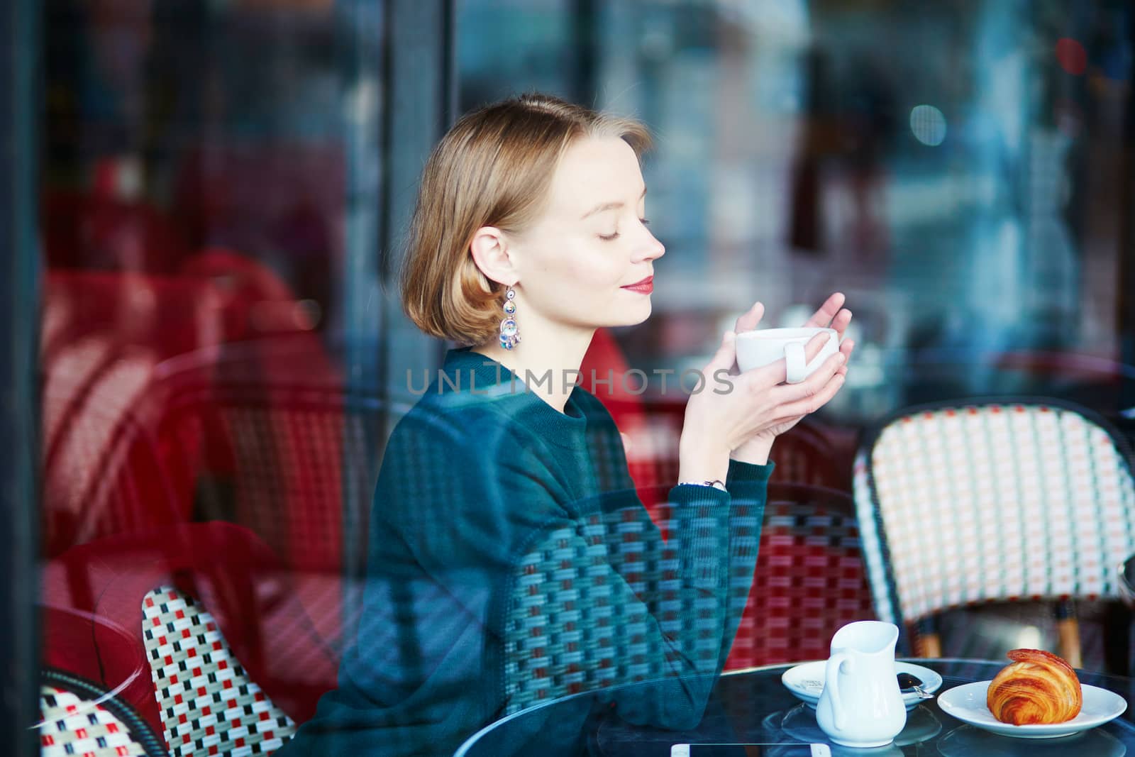 Young elegant woman drinking coffee in traditional cafe in Paris, France