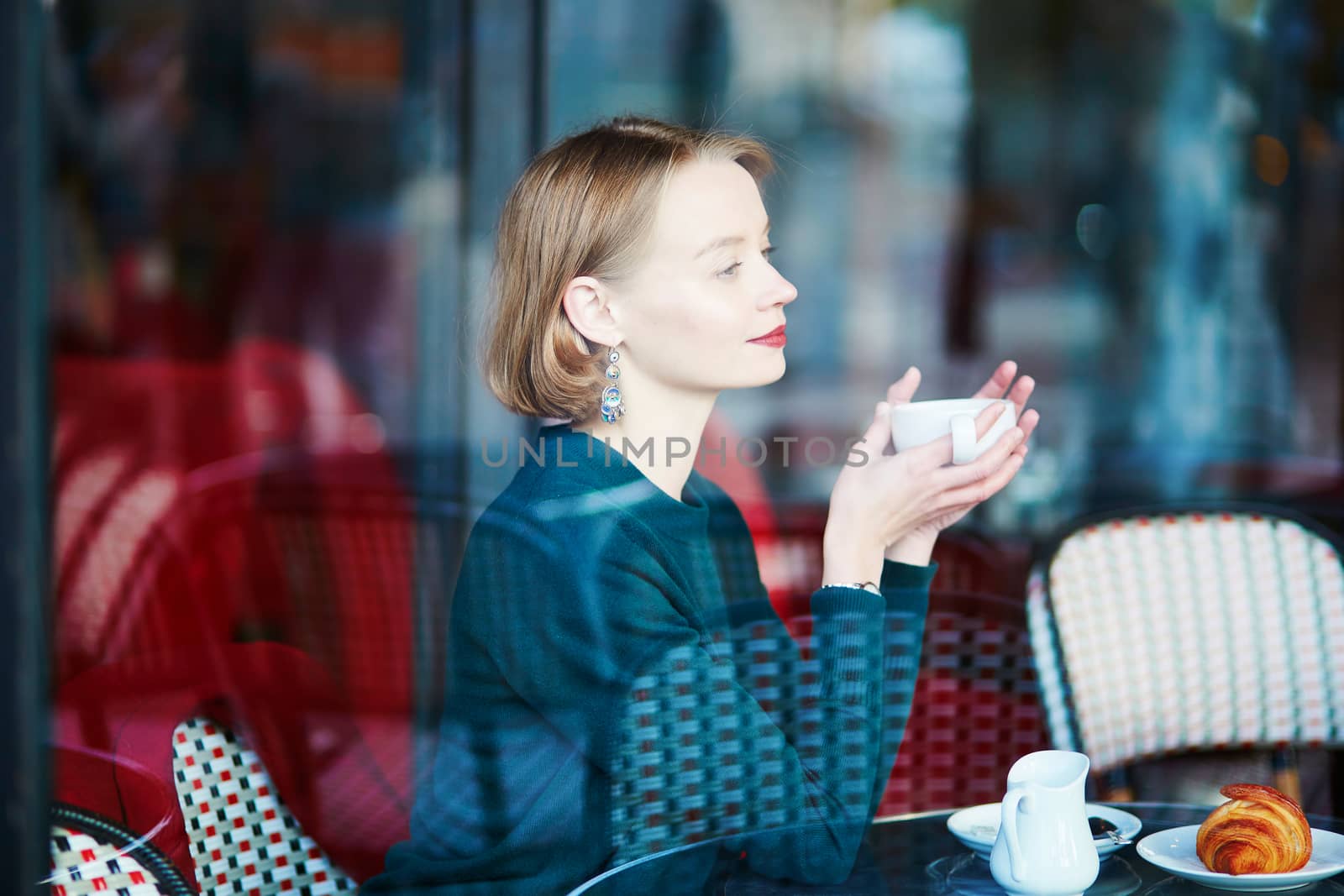 Young elegant woman drinking coffee in traditional cafe in Paris, France