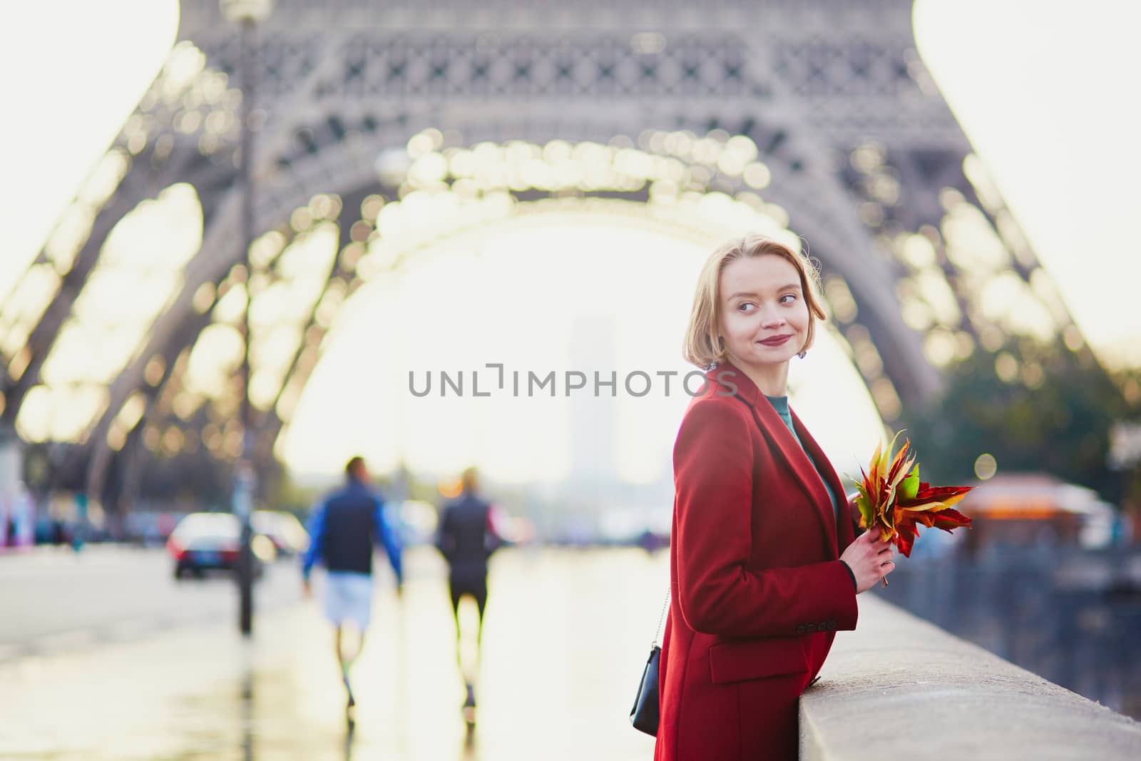 Beautiful young French woman drinking coffee near the Eiffel tower in Paris on a fall or spring day