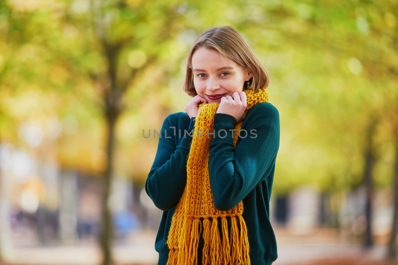 Happy young girl in yellow scarf in autumn park on a bright fall day