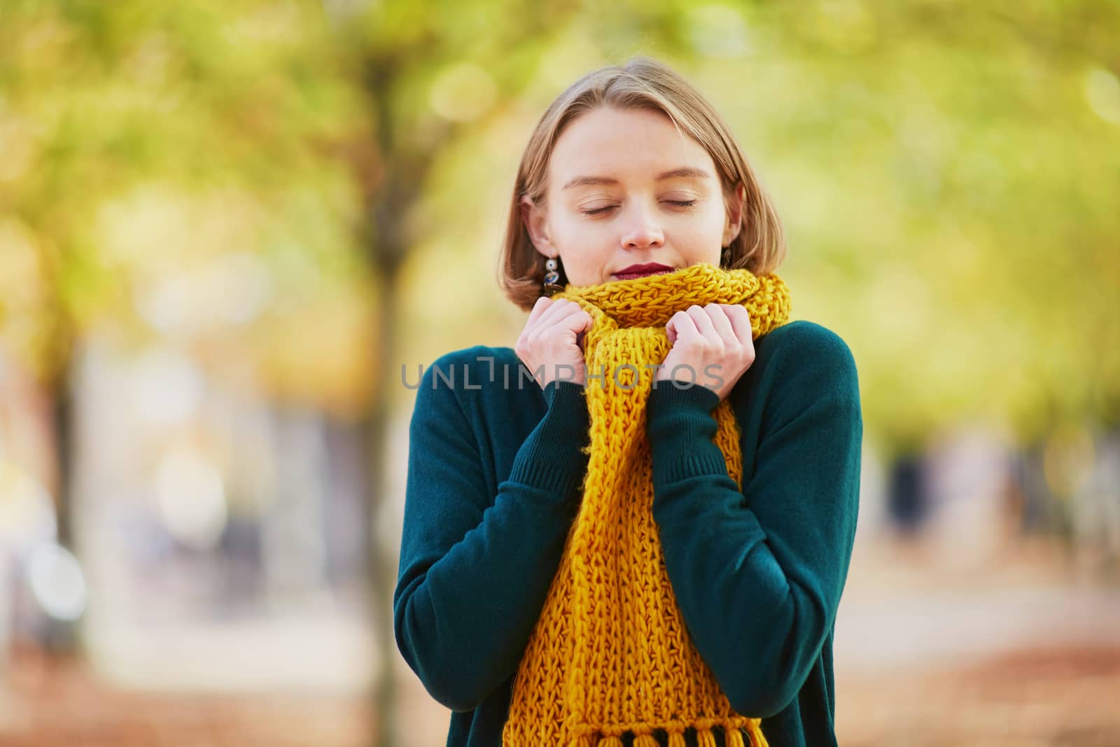 Happy young girl in yellow scarf in autumn park on a bright fall day