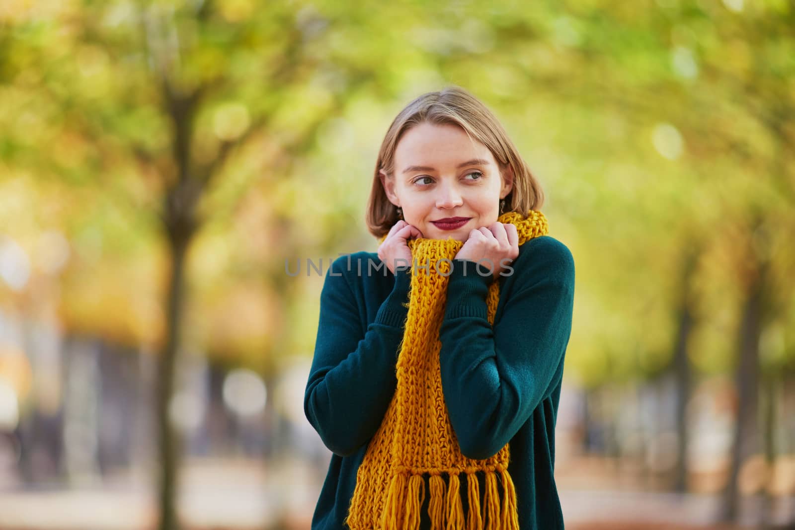 Happy young girl in yellow scarf in autumn park on a bright fall day