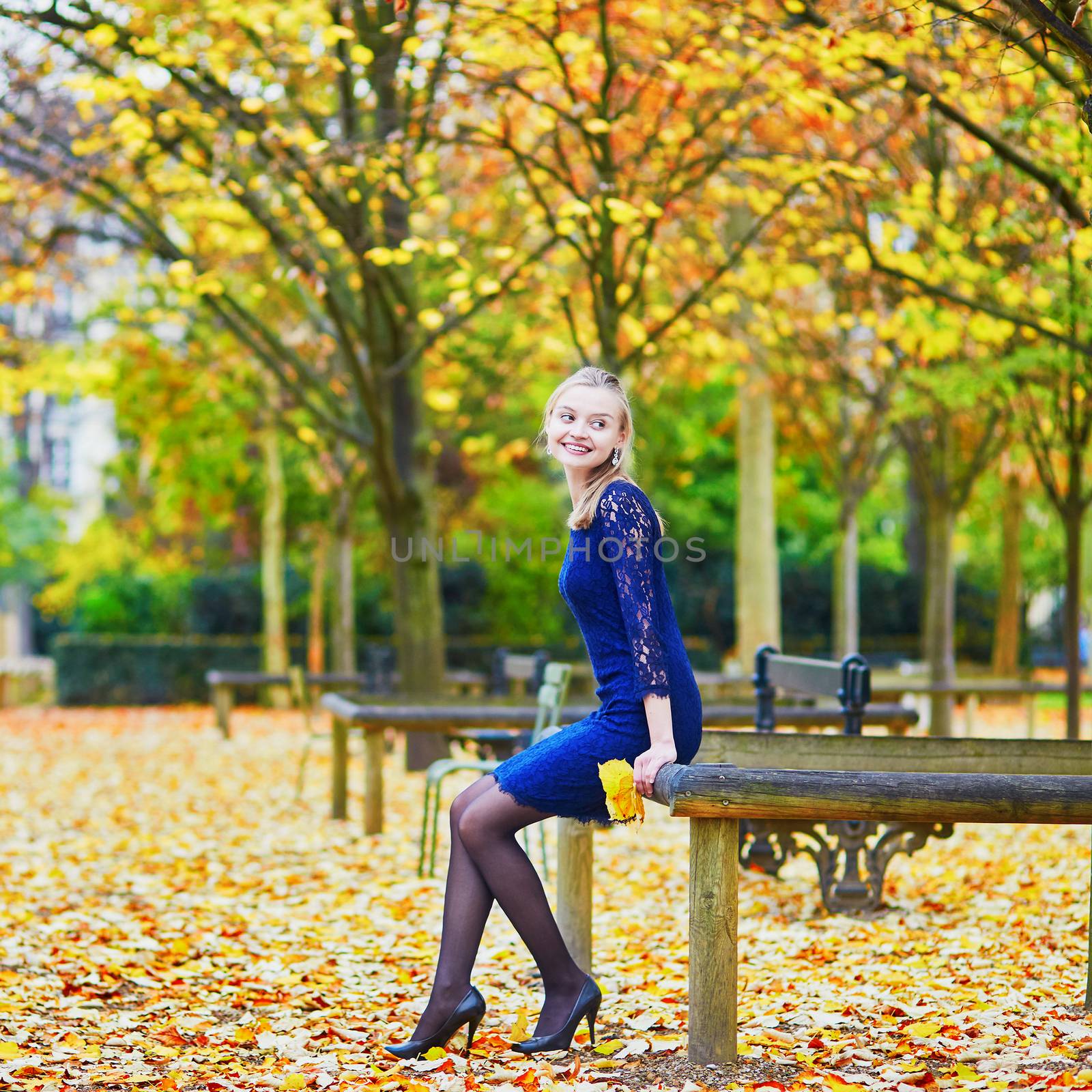 Beautiful young woman in blue dress in the Luxembourg garden of Paris on a fall day