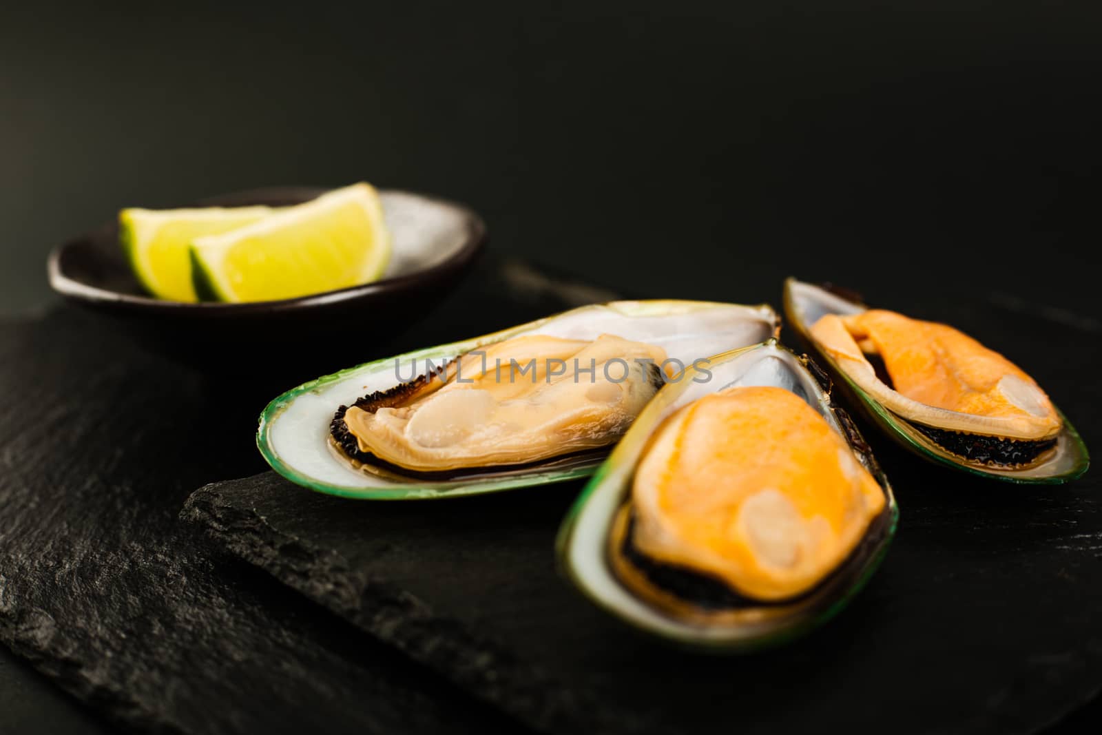New Zealand greenshell mussels on black stone plate background and lime stylish luxury studio shot