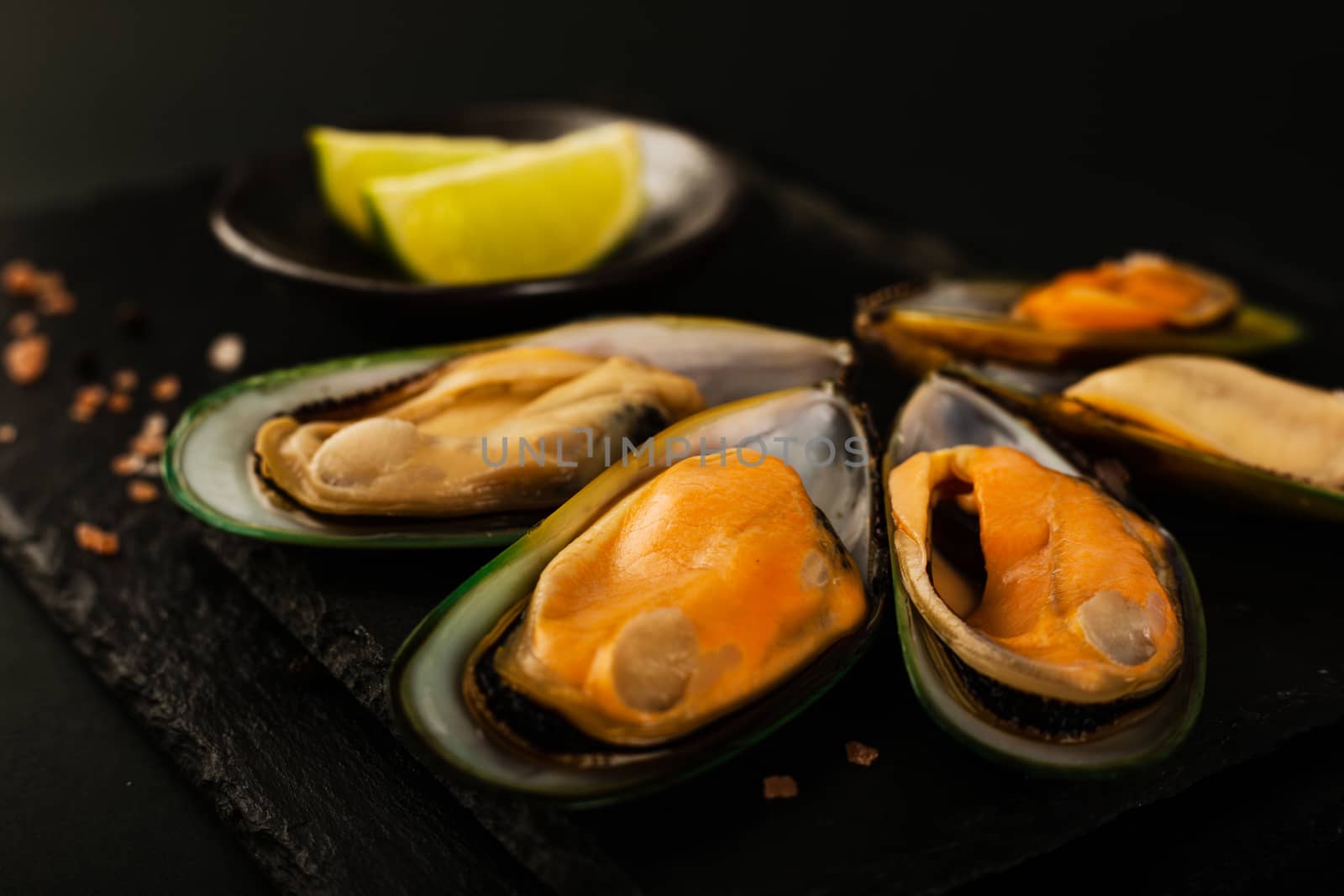 New Zealand greenshell mussels on black stone plate background and lime stylish luxury studio shot