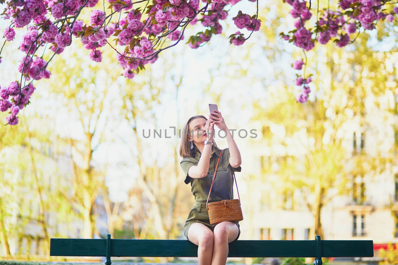 Beautiful French woman walking in Paris on a spring day at cherry blossom season