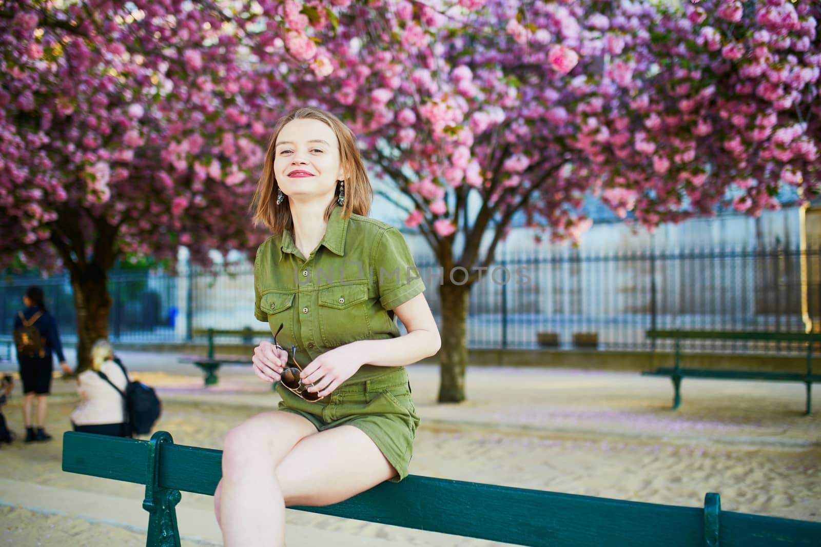 Beautiful French woman walking in Paris on a spring day at cherry blossom season