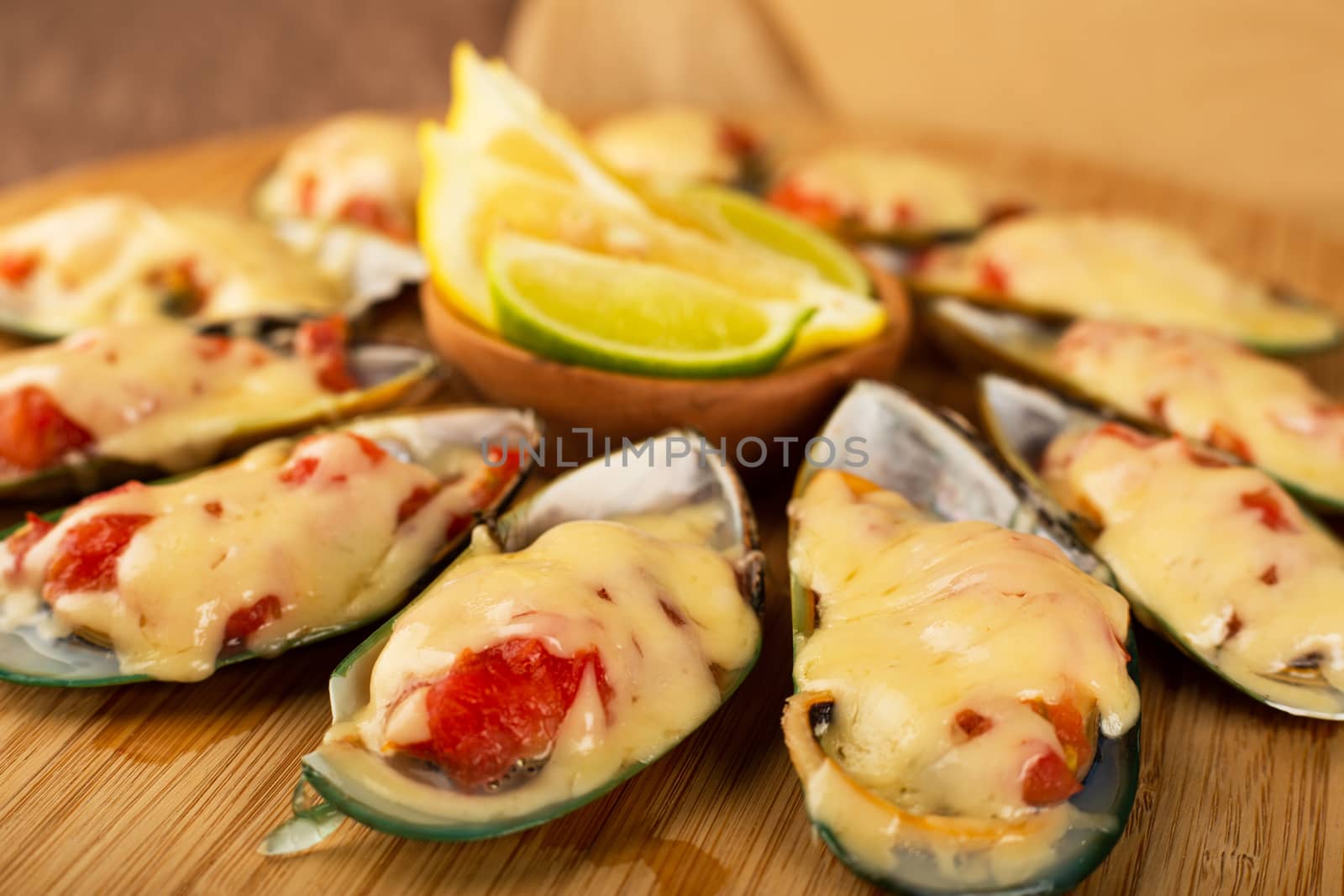 Seafood. Mussel clams. Baked greenshell mussels with tomato and cheese, cilantro and lemon on wooden background