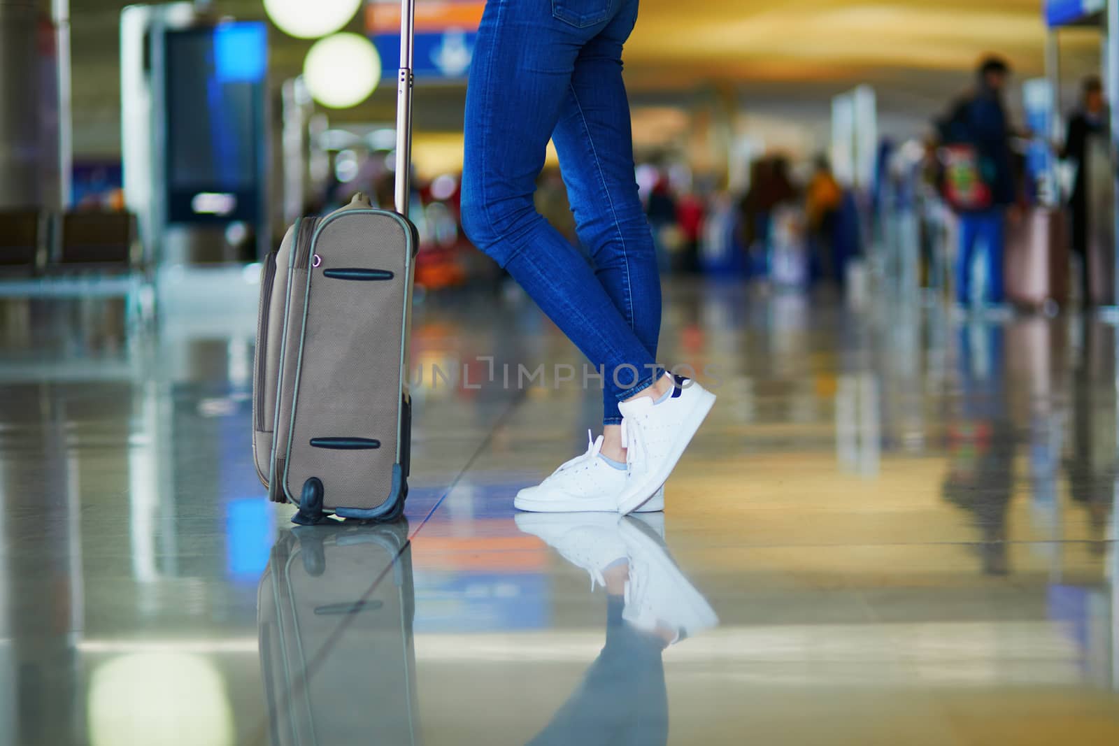 Closeup of woman legs with luggage in international airport. Tourism and travel concept