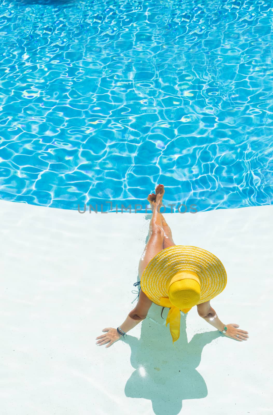 beautiful woman in a hat sitting on the edge of the pool by Netfalls