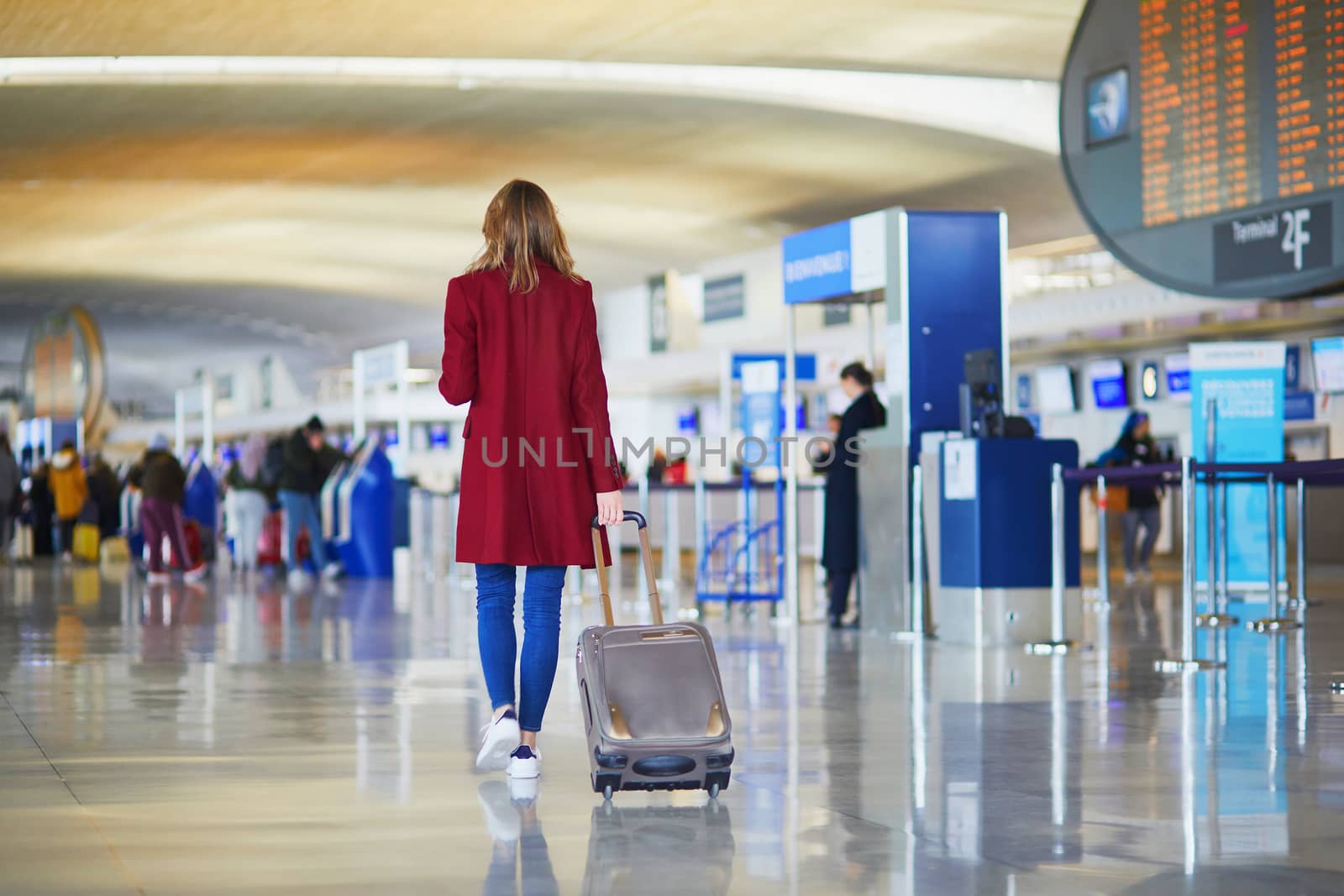 Young woman in international airport walking with luggage, ready for her flight