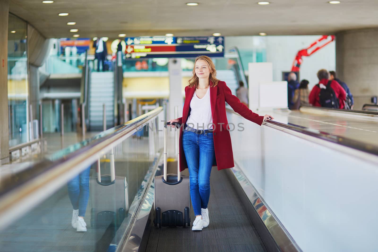 Young woman in international airport with luggage on travelator