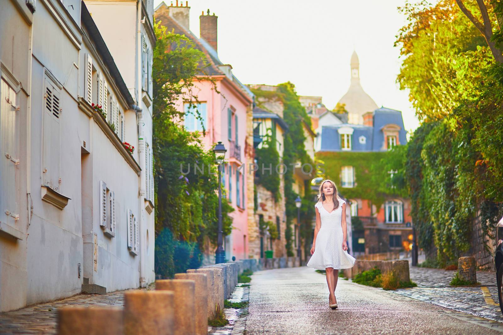 Beautiful young woman in white dress walking on famous Montmartre hill in Paris, France at early morning