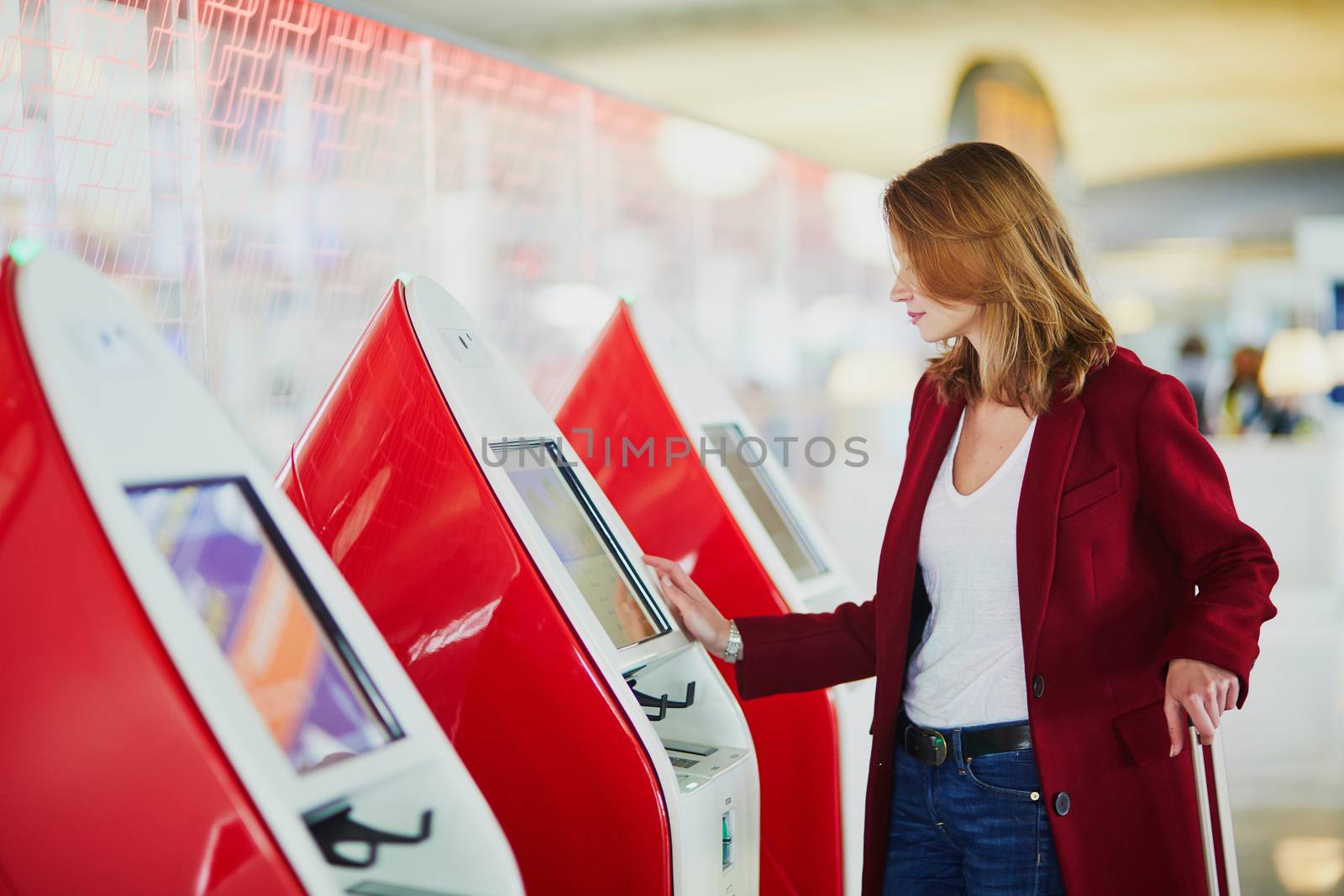 Young woman in international airport doing self check-in