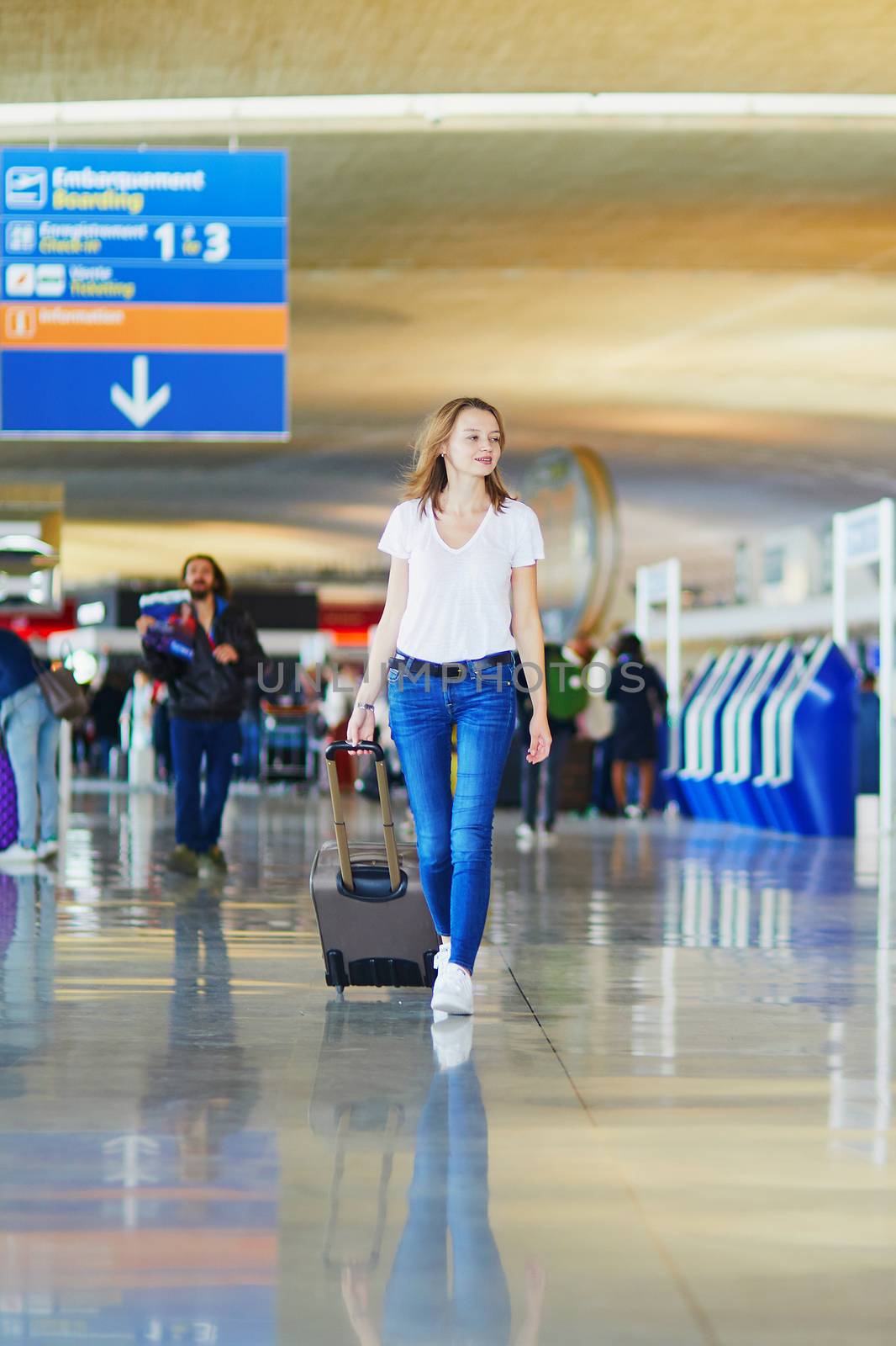 Young woman in international airport walking with luggage, ready for her flight