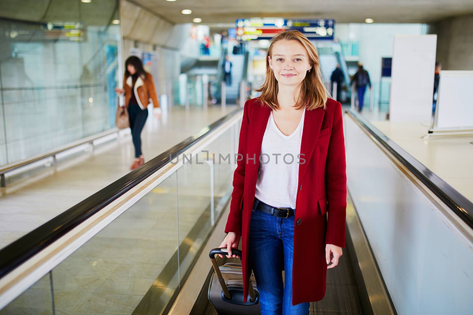 Young woman in international airport with luggage on travelator