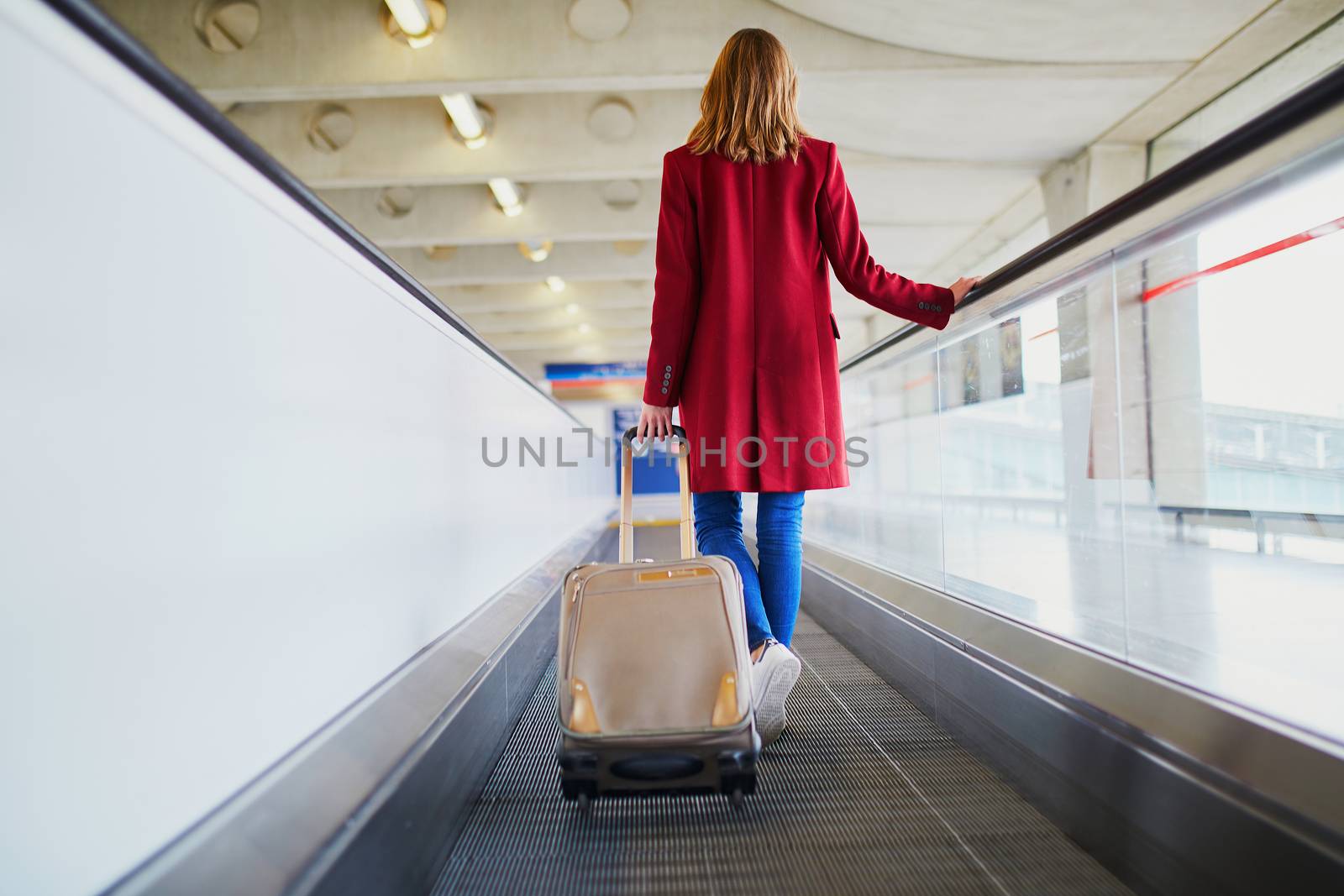 Young woman in international airport with luggage on travelator