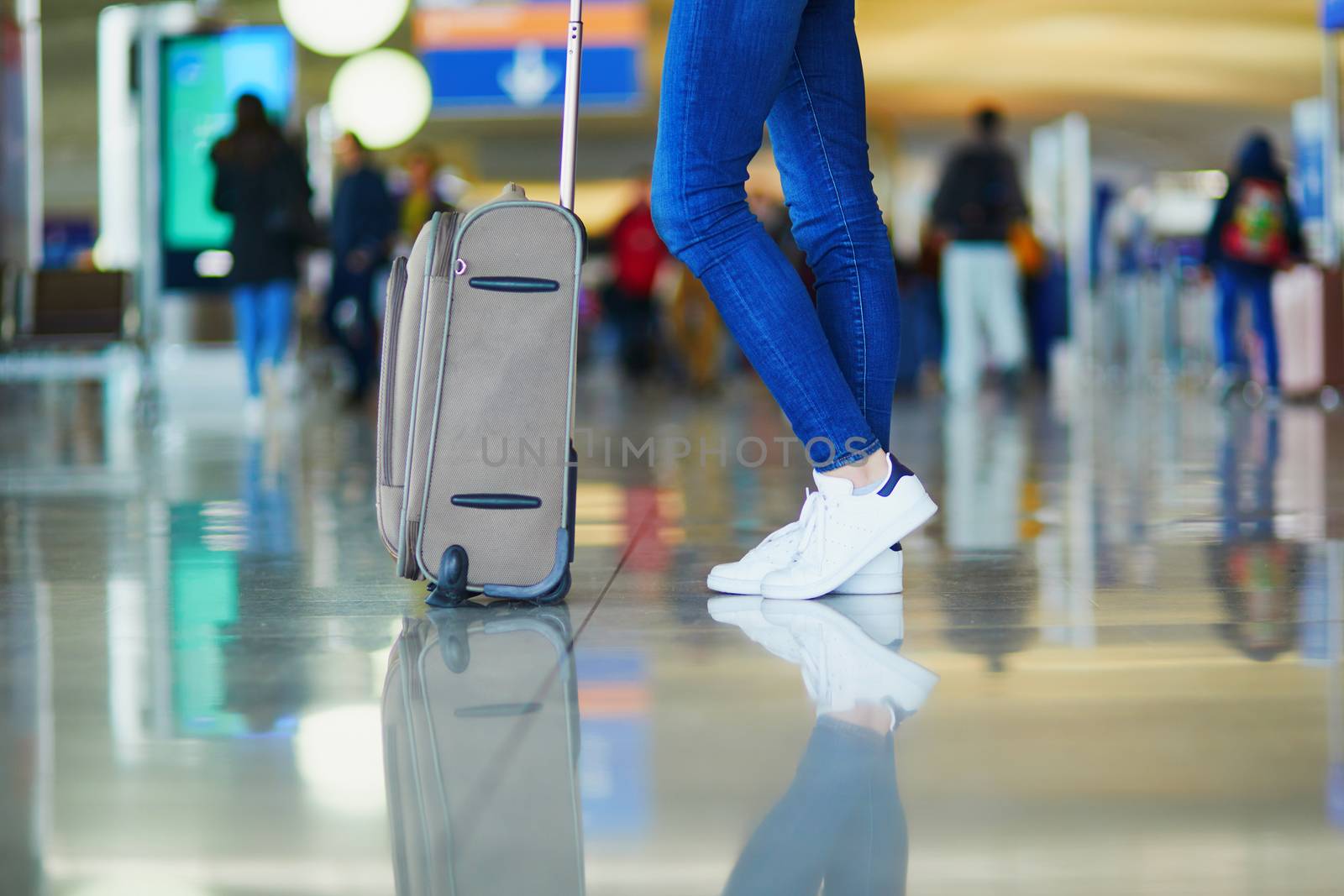 woman legs with luggage in international airport by jaspe