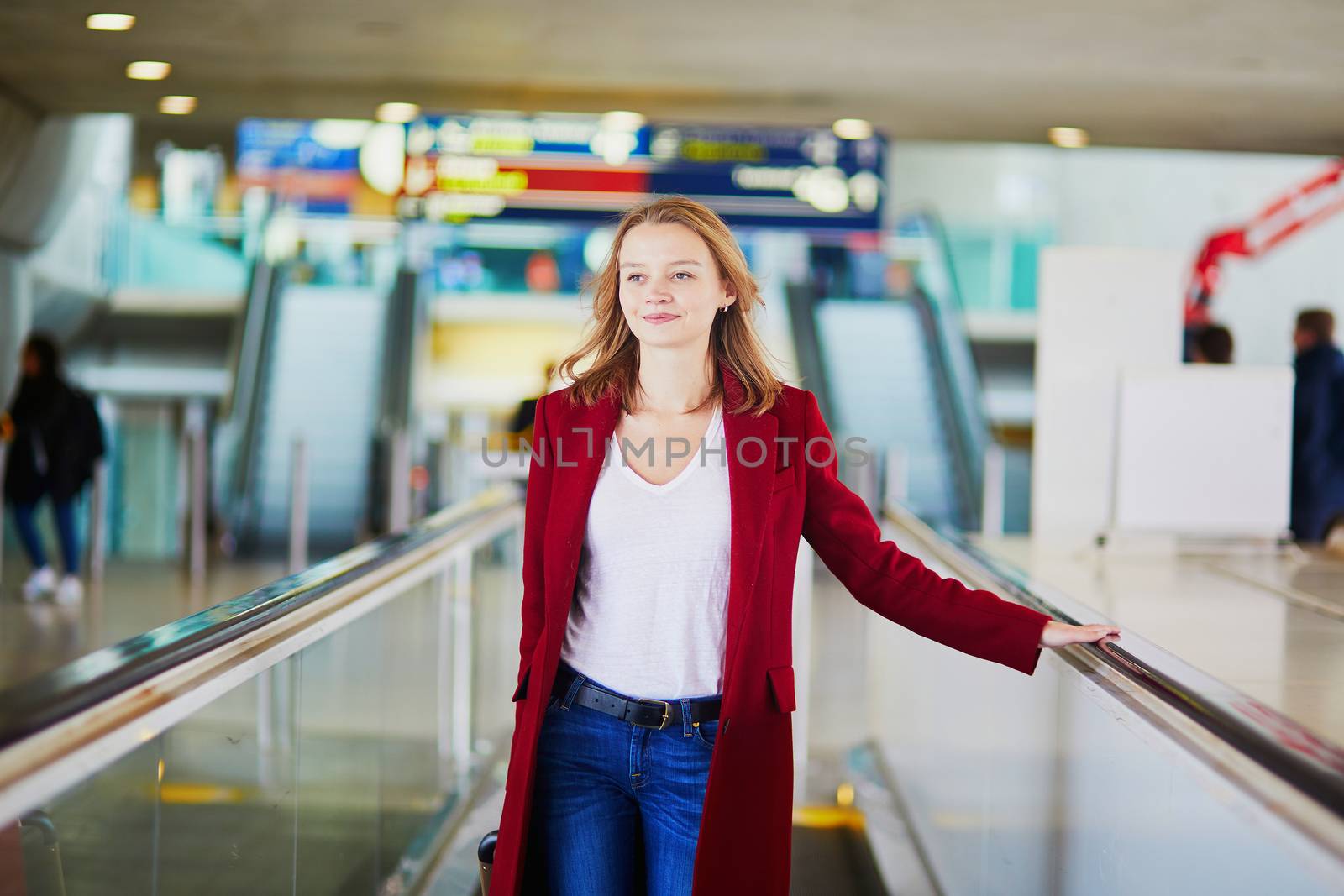 Young woman in international airport with luggage on travelator