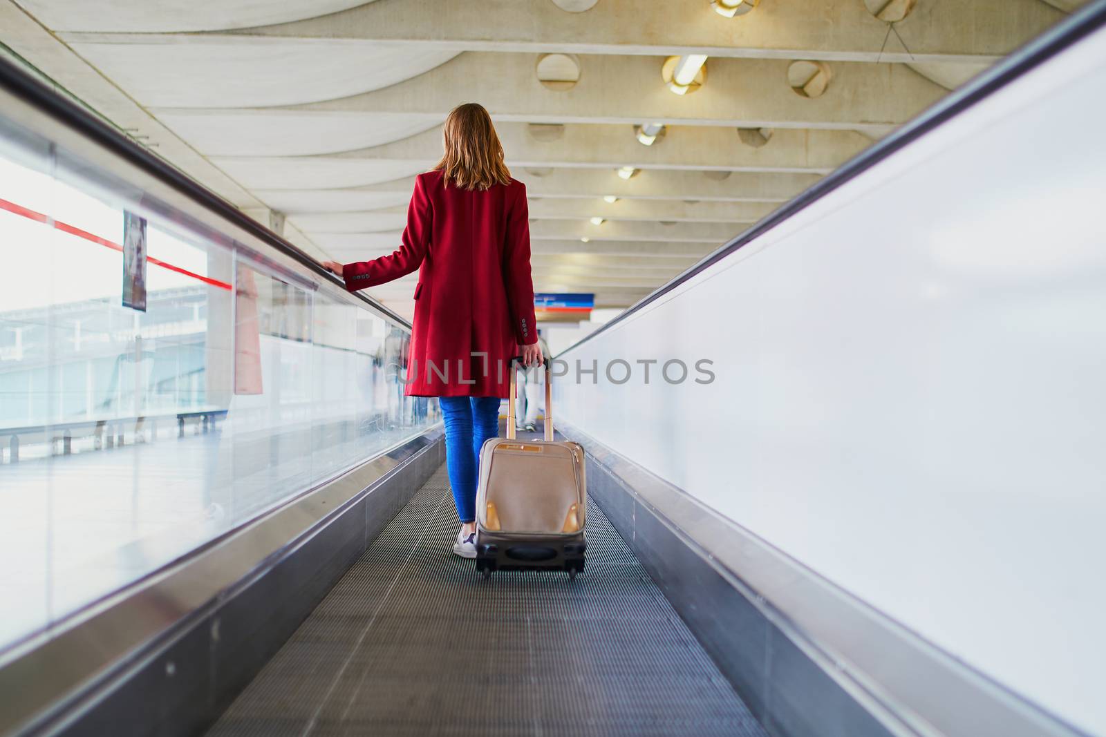 Young woman in international airport with luggage on travelator