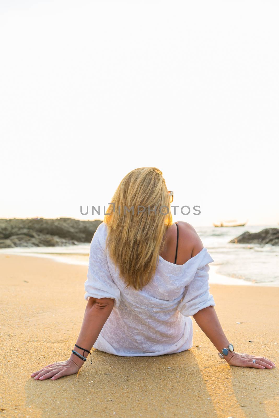 young woman is sitting on beach at sunrise in Khao Lak Thailand